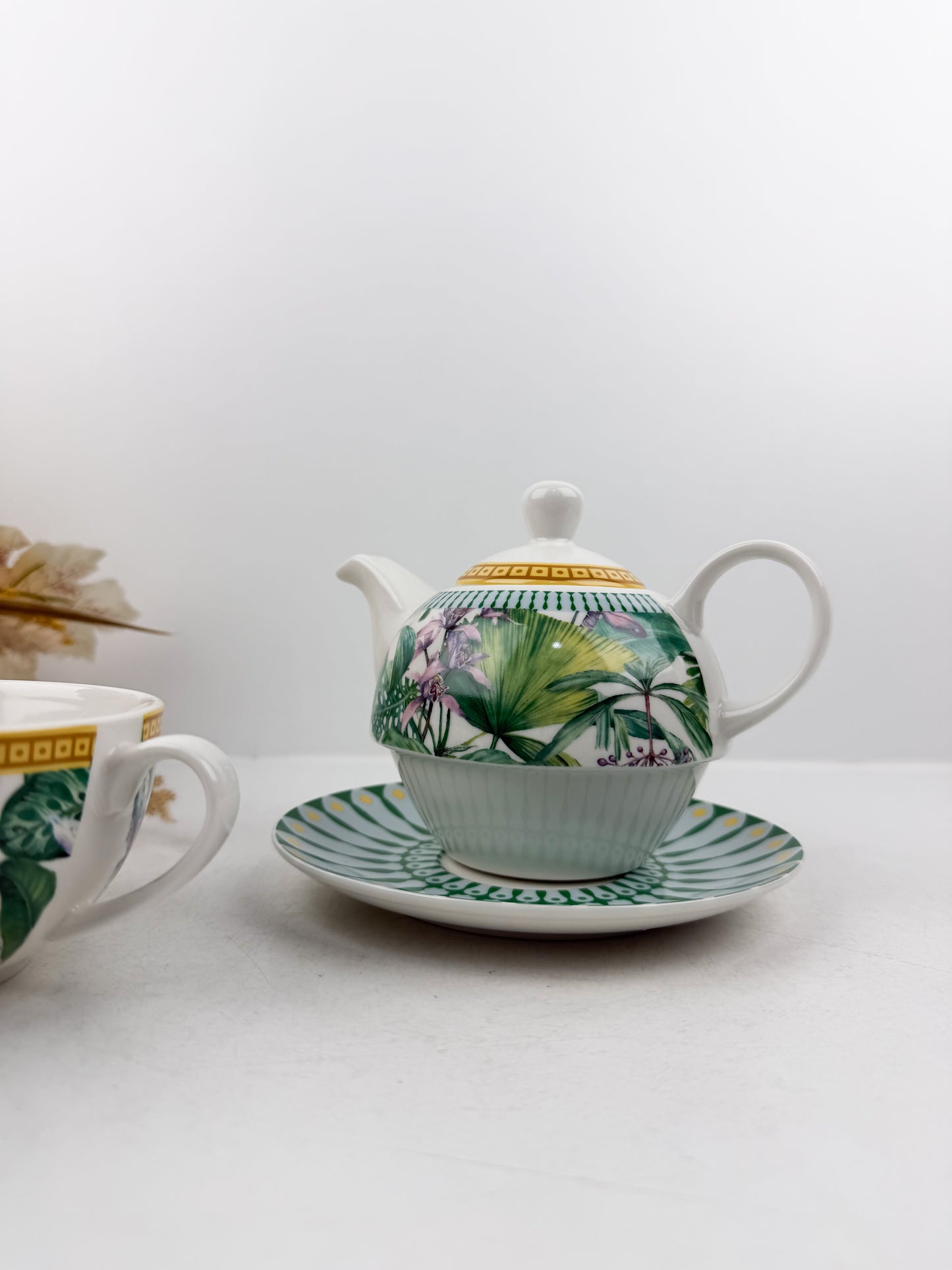 Théière élégante d'une tasse accompagnée de sous-tasse raffinée de motif jungle