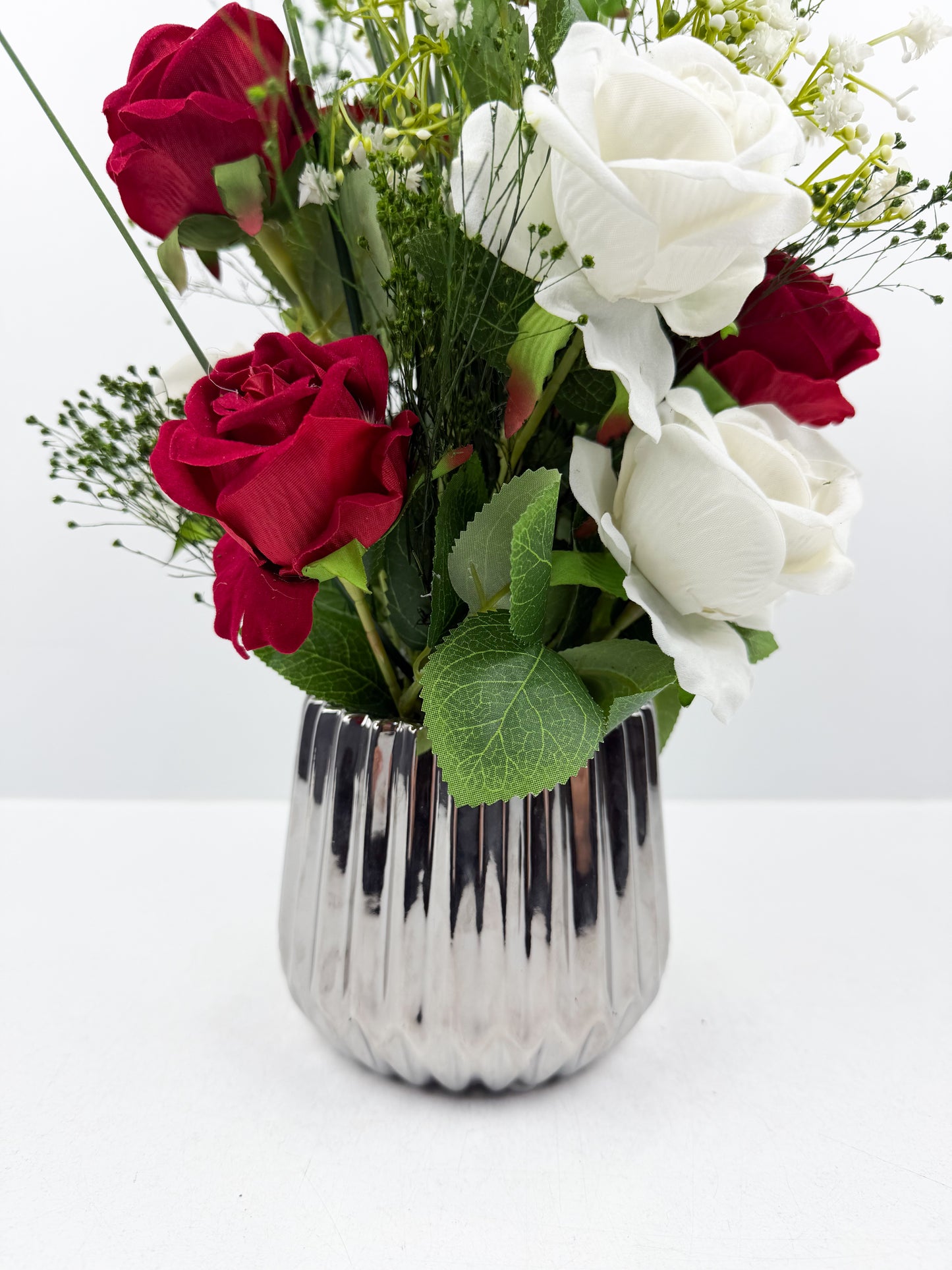 Fleurs artificielles blanches et rouges d'une élégance intemporelle dans un vase argenté brillant