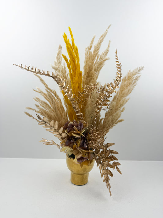Fleurs séchées marron foncé arrangé avec élégance dans un vase en céramique doré