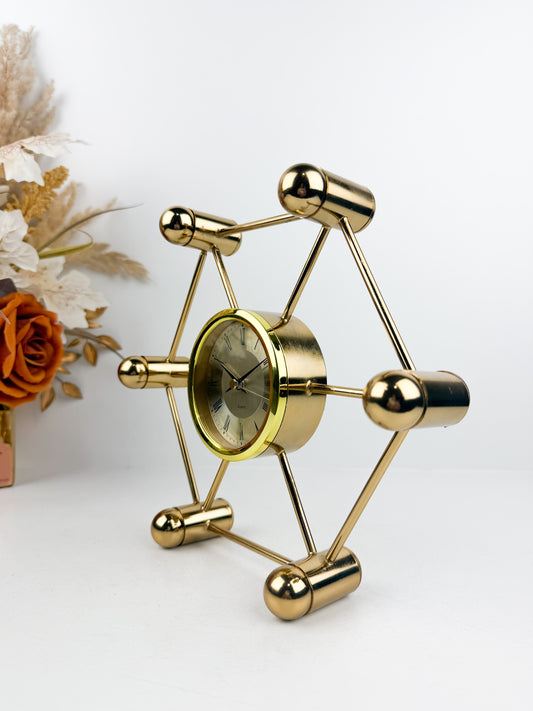 Horloge décoratif en métal doré aux lignes géométriques épurées.
