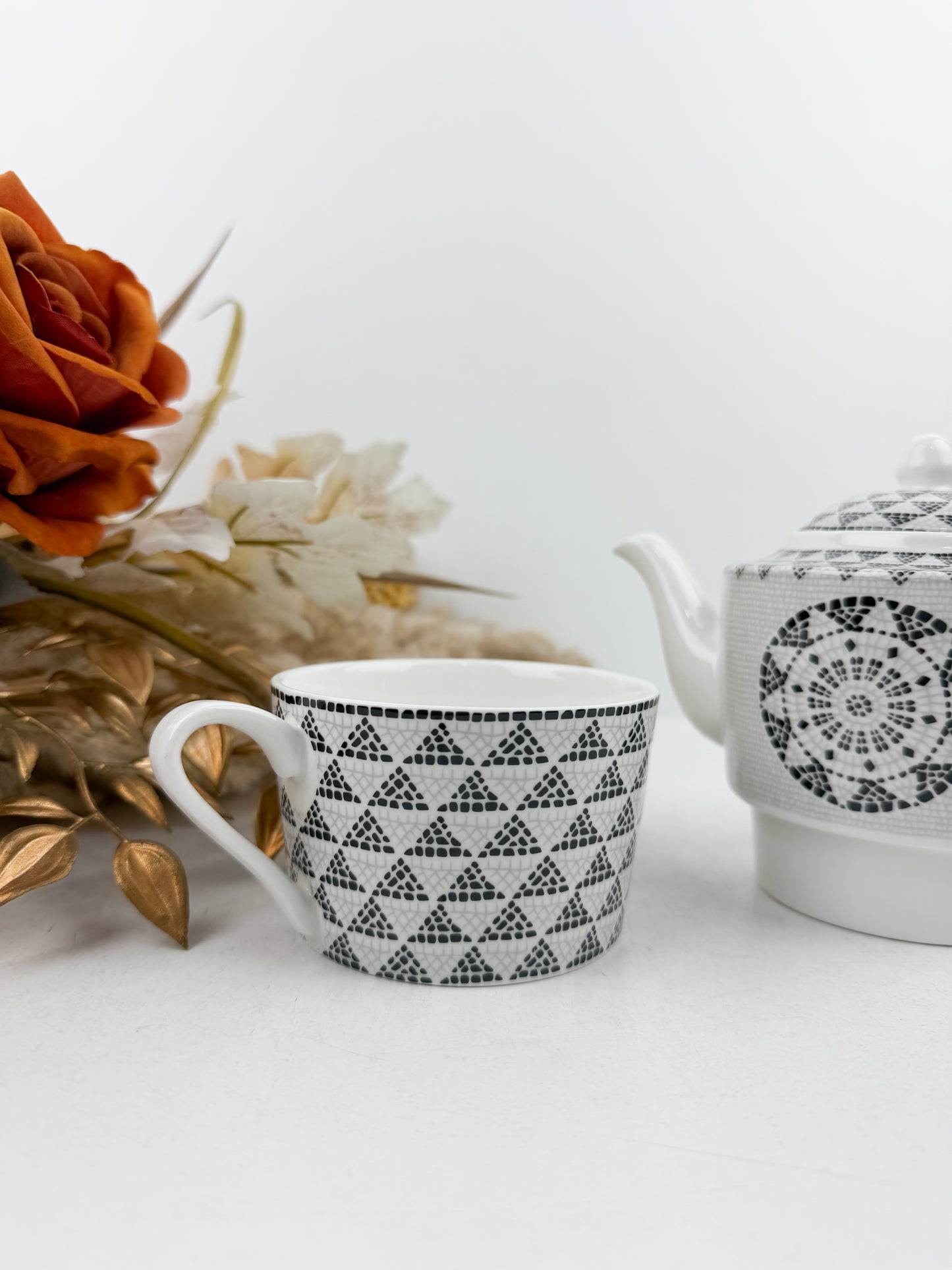 Théière élégante accompagnée d'une tasse à café au lait aux motifs treillis noir et blanc