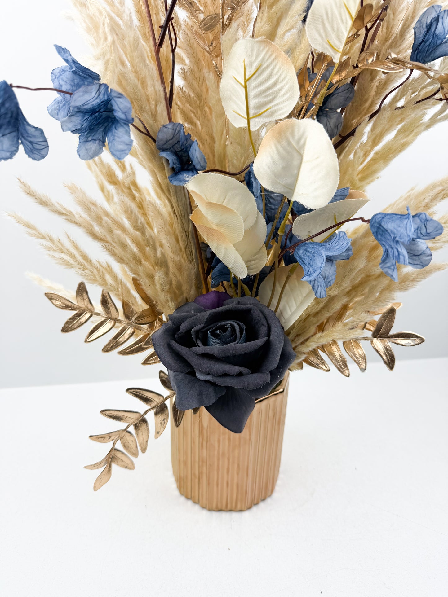 Fleurs séchées dans un vase en céramique doré au design élégant et luxueux.