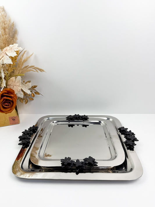 Plateaux carrée avec des poignées florales noires.