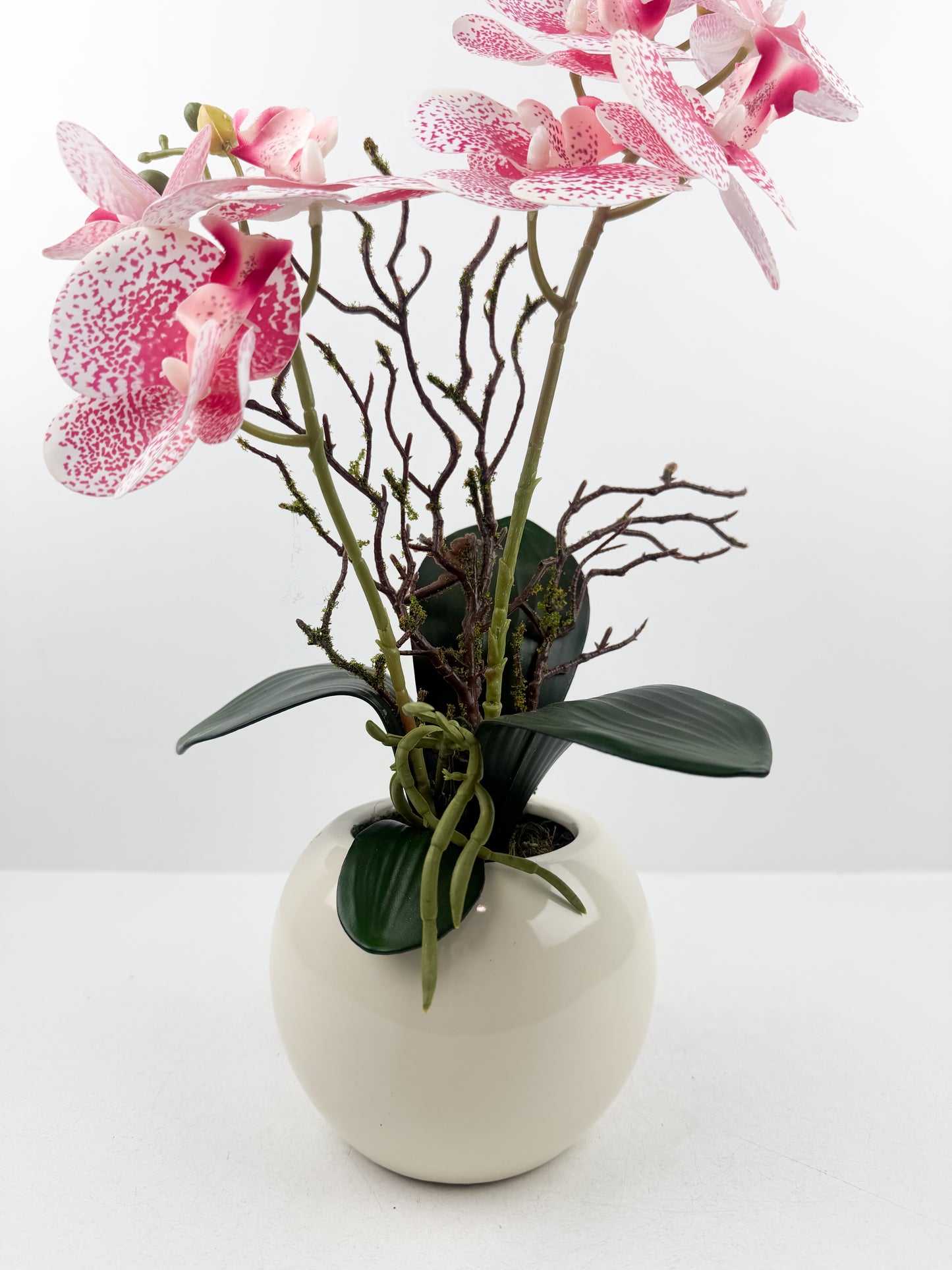 Fleurs artificielles roses de luxe dans un pot beige haut de gamme de forme ronde
