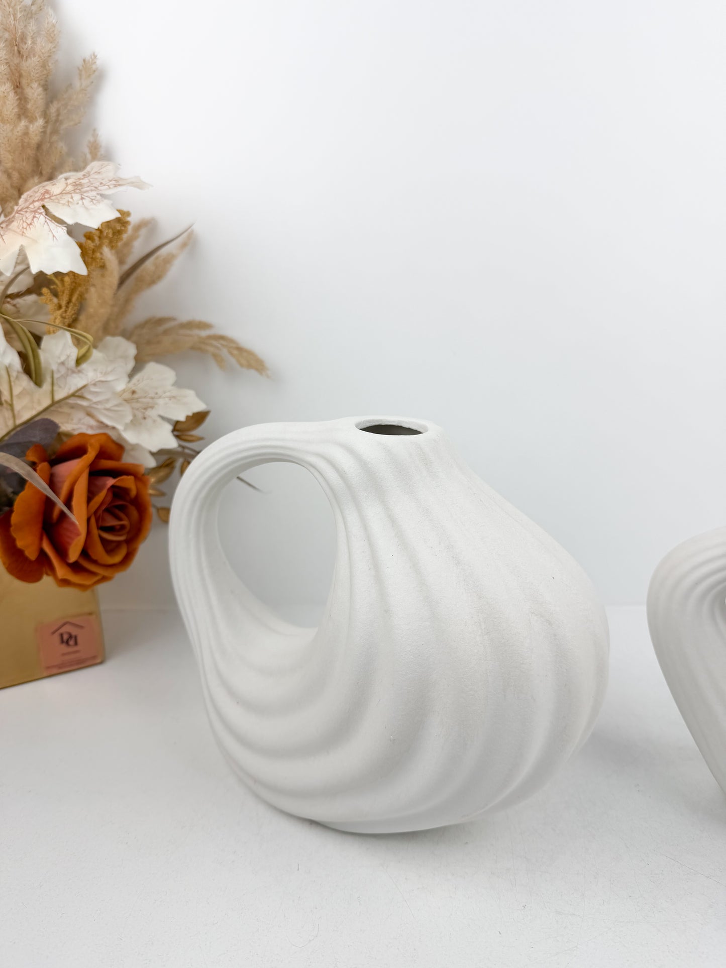 Duo de vases en céramique blanc mat aux formes géométriques épurées.