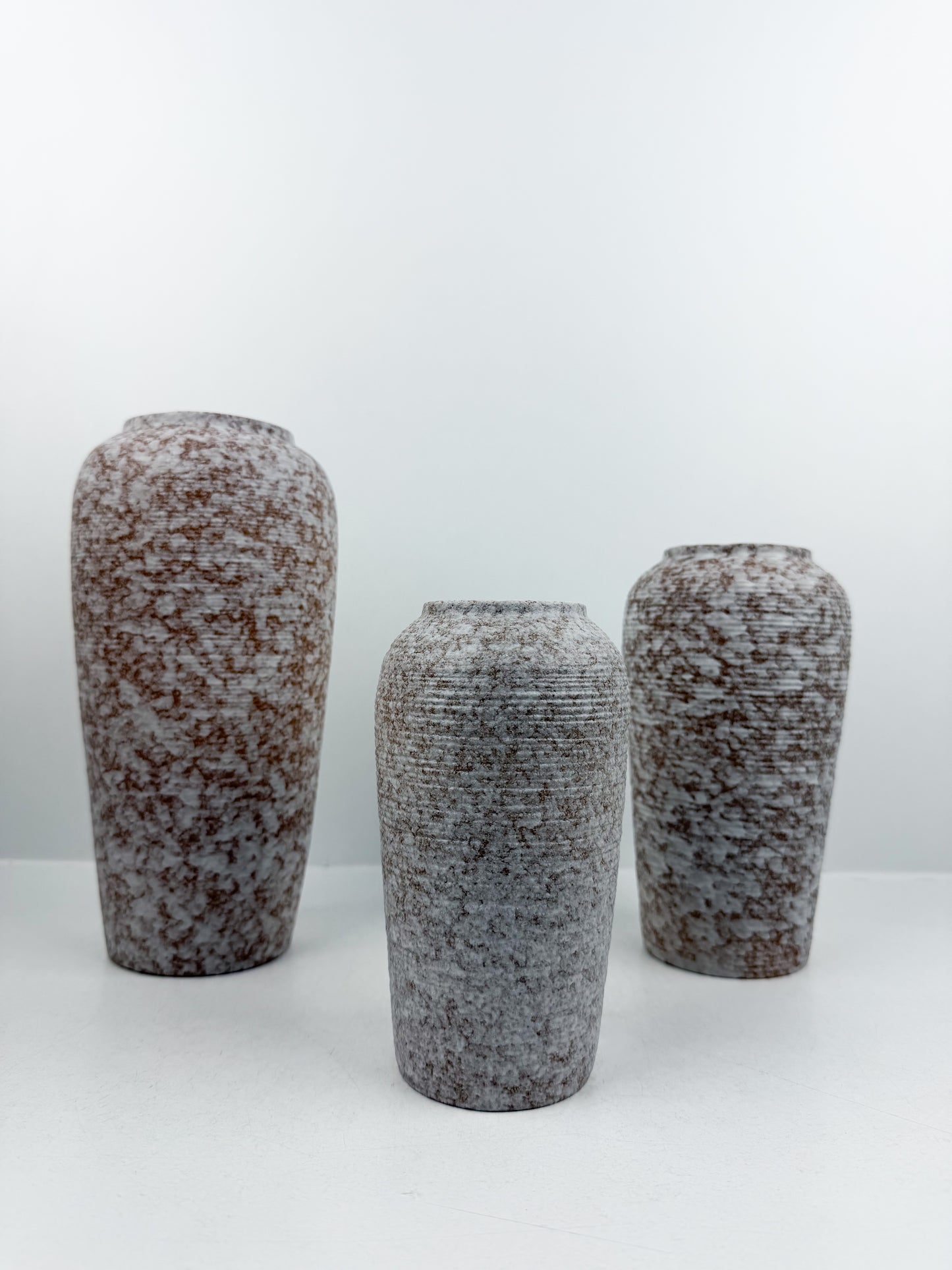 Trio de vases aux teintes marron et blanc en céramique alliant élégance et raffinement.