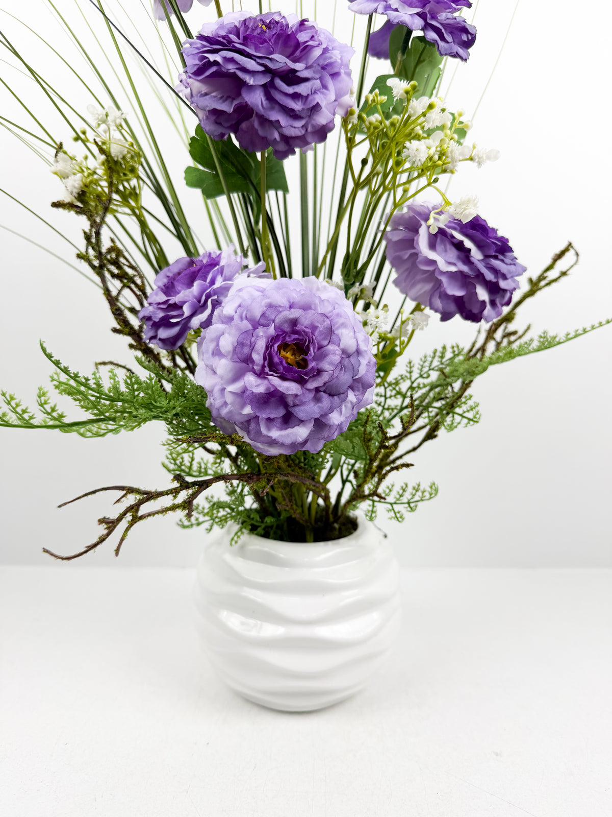 Fleurs séchées violettes délicate dans un vase en céramique aux lignes épurées.