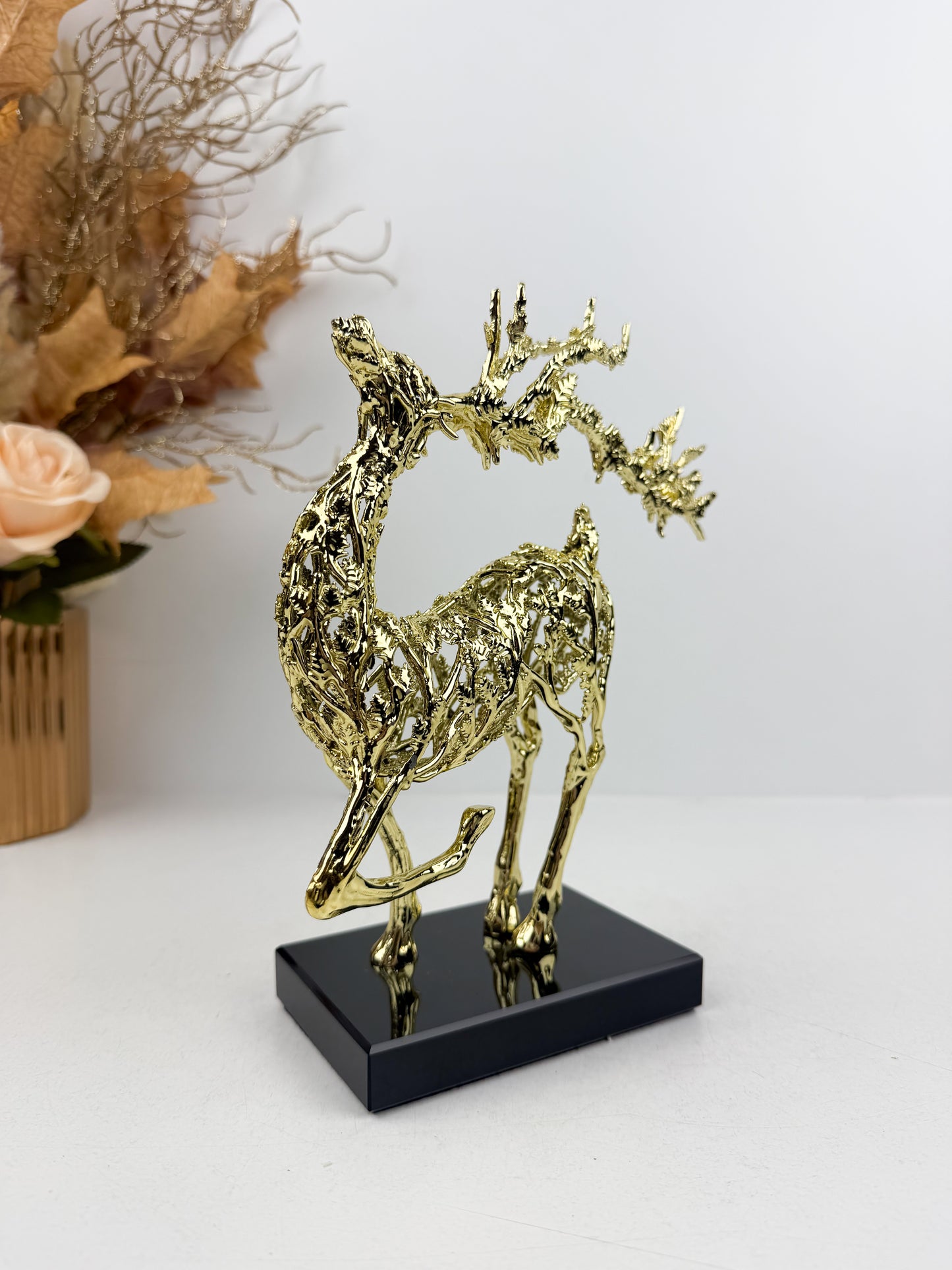 Sculpture de gazelle dansante en métal doré sur un socle noir en cristal , incarnant l'élégance et la grâce.