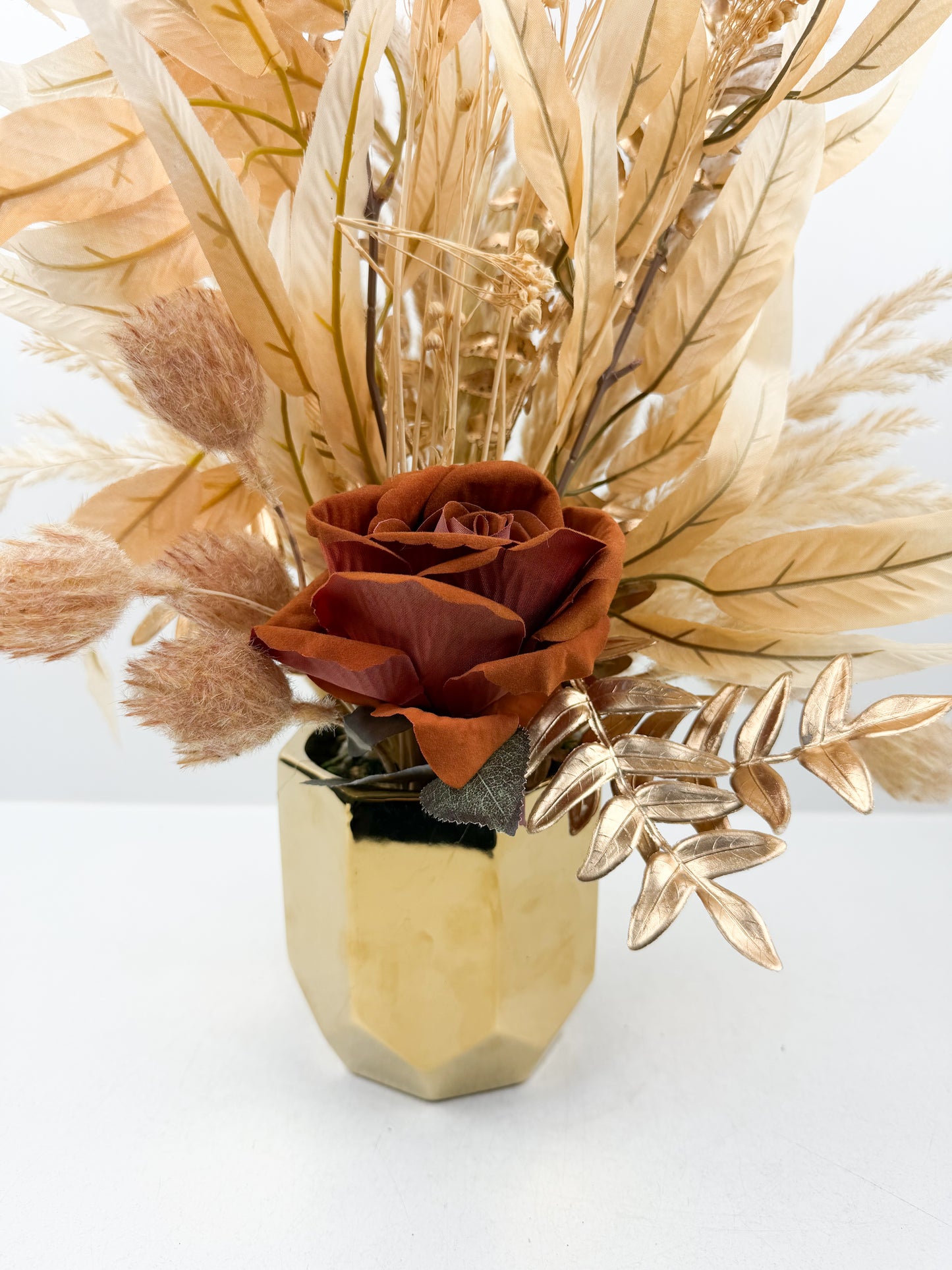Fleurs séchées marron avec une fleure marron foncé luxe avec élégance dans un pot en céramique doré aux finitions miroir.