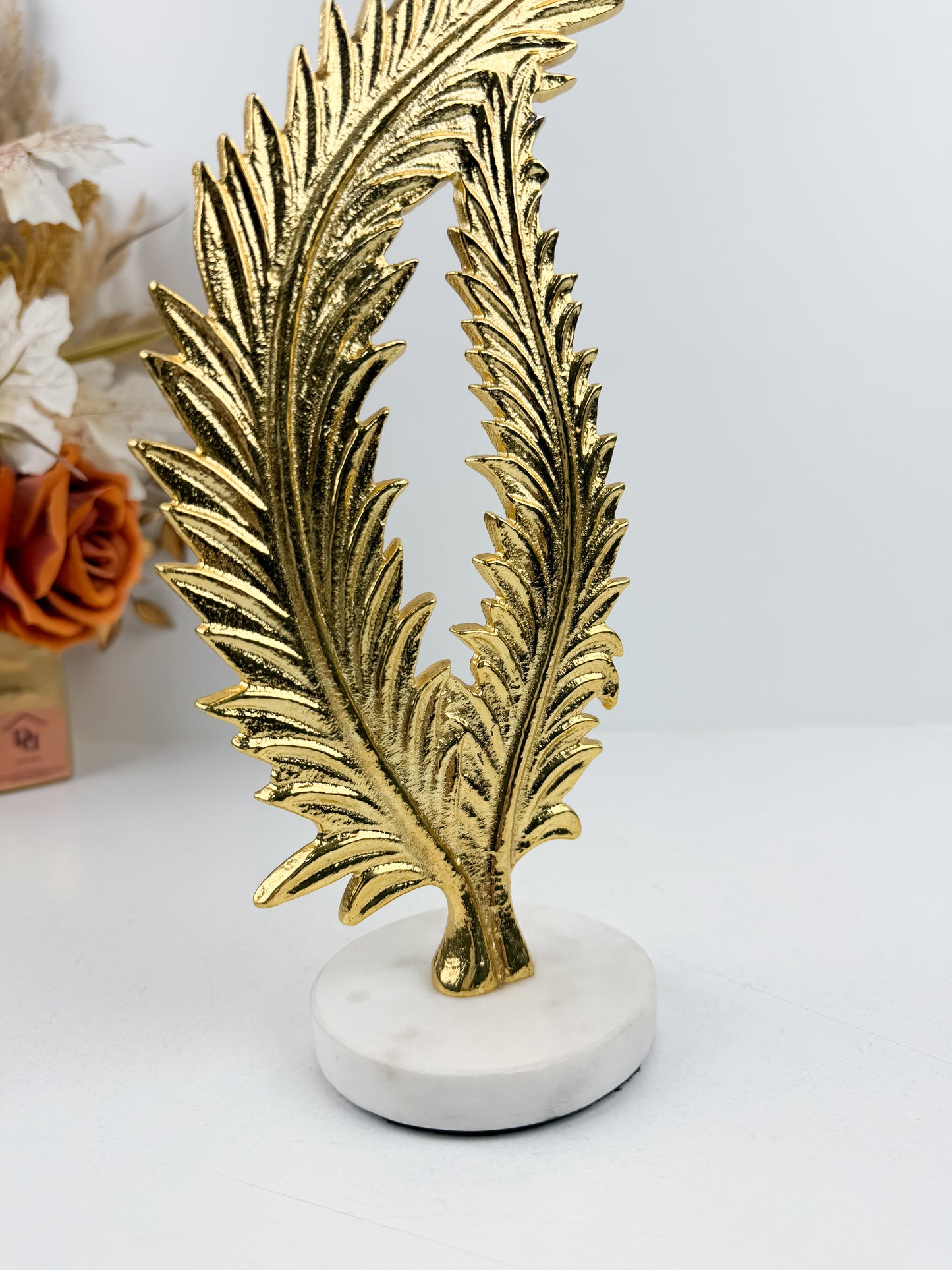 Sculpture décorative élégante représentant une feuille de fougère stylisée en métal doré.