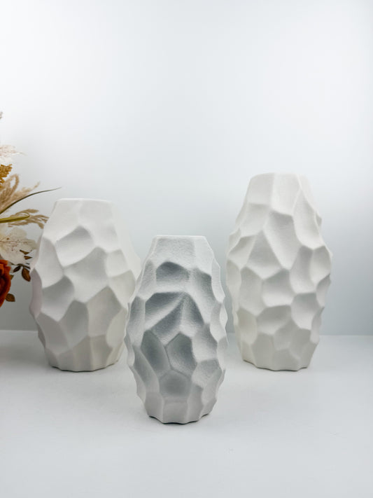 Trio de vases blanches aux formes sculpturales épurées.