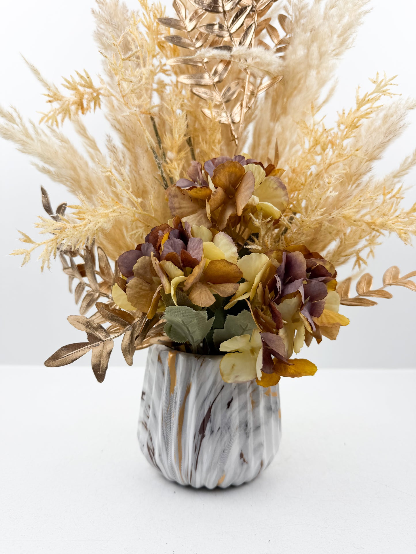 Fleurs séchés marron d'une élégance intemporelle dans un vase en forme de marbre raffiné.
