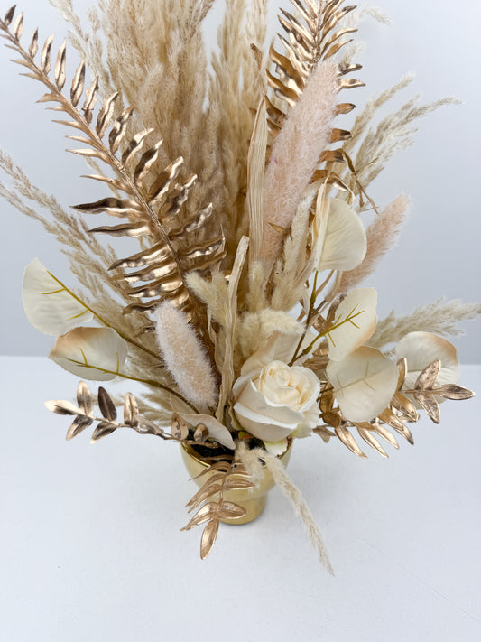 Fleurs séchées beige arrangé avec élégance dans un vase en céramique doré