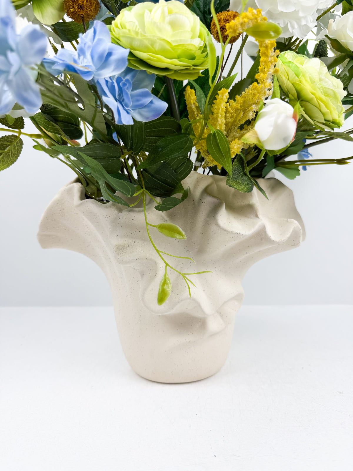 Fleurs artificielles dans un vase en céramique texturée au design original.