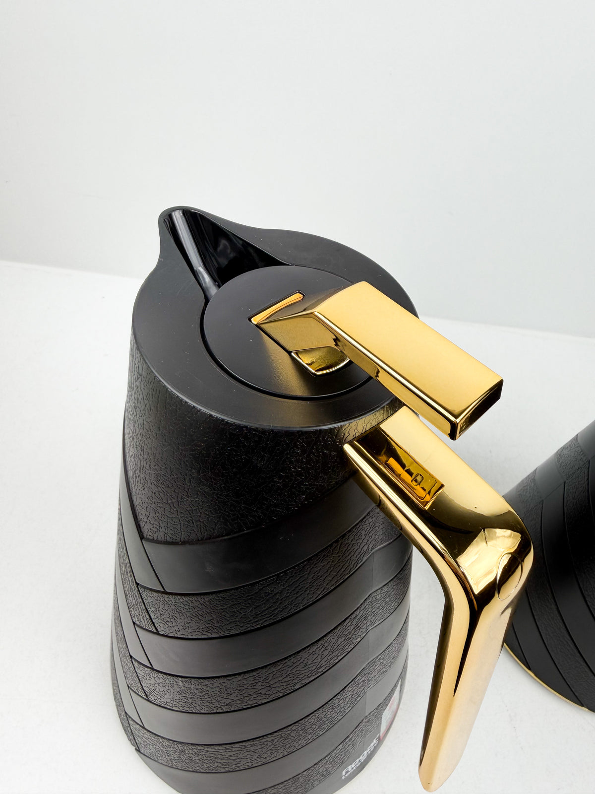Duo de thermos isothermes noirs mats avec motifs chevrons en relief, anses et détails dorés.
