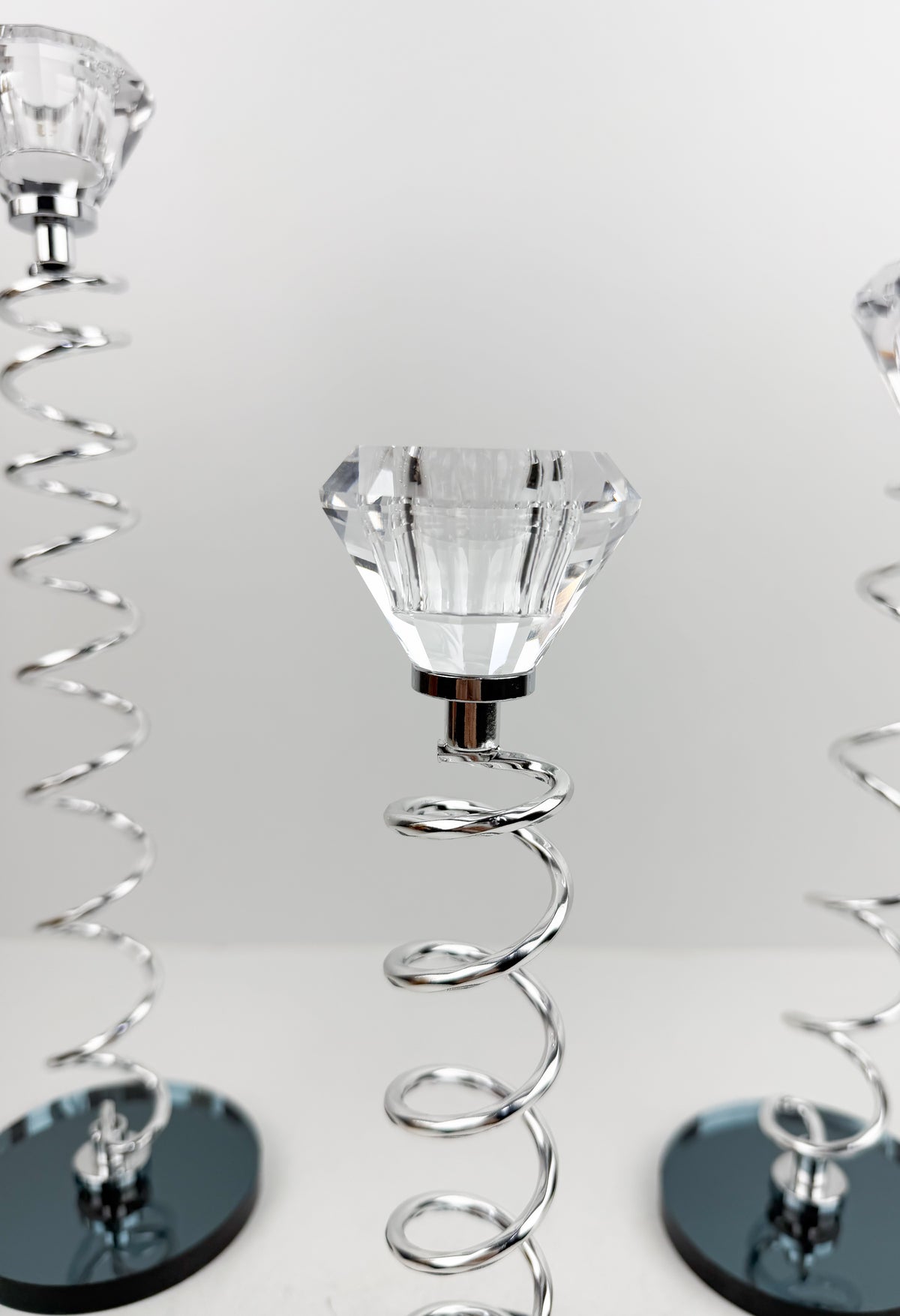 Trio de Bougeoirs en cristal argentée sur un socle noir.