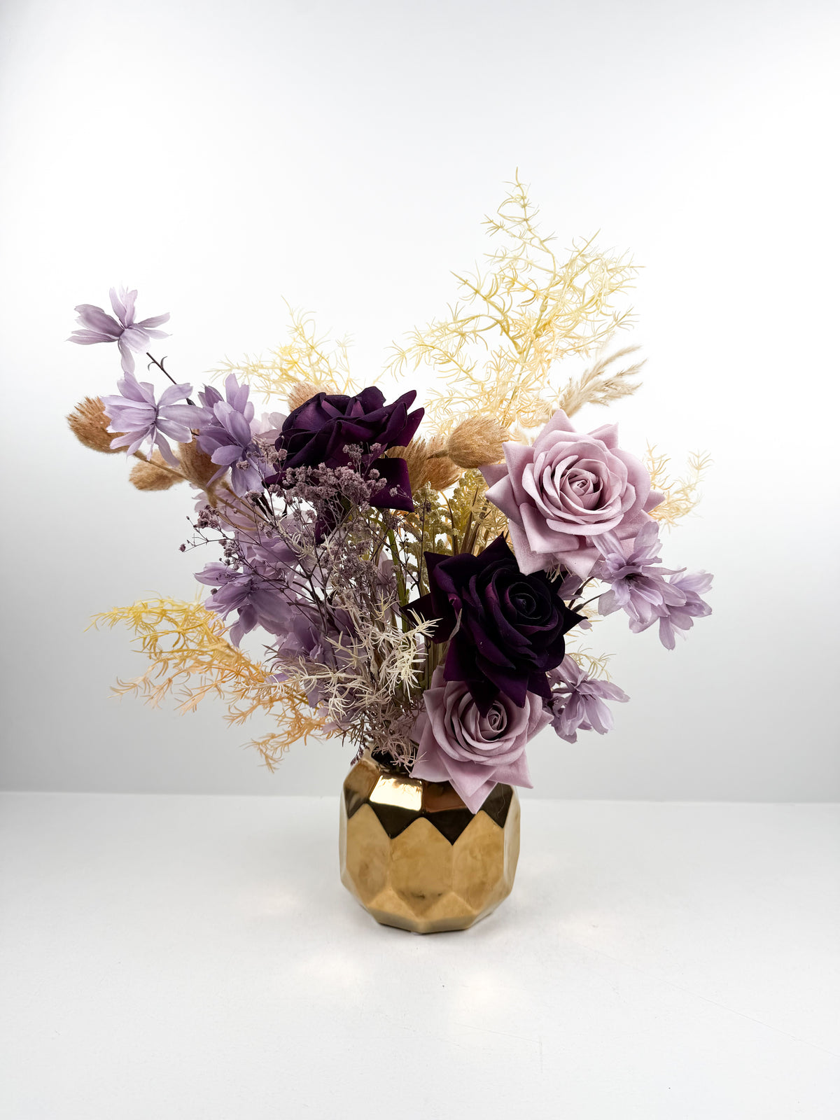 Fleurs séchées délicates dans un élégant vase géométrique en céramique dorée.