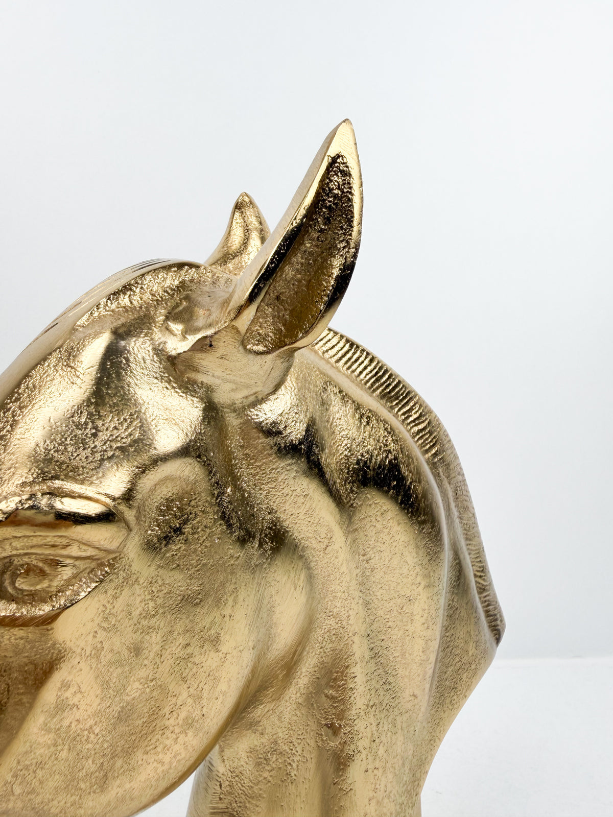 Sculpture décorative en métal doré brillant représentant une tête de cheval.