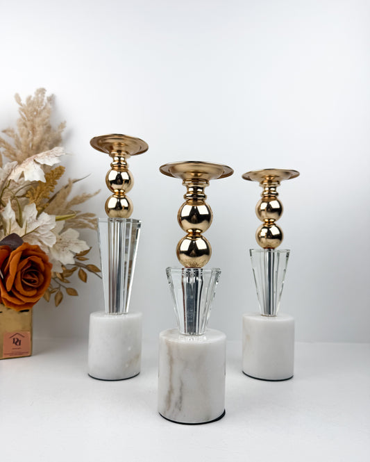 Ensemble élégant de bougeoirs en cristal et métal doré sur un socle en marbre blanc.