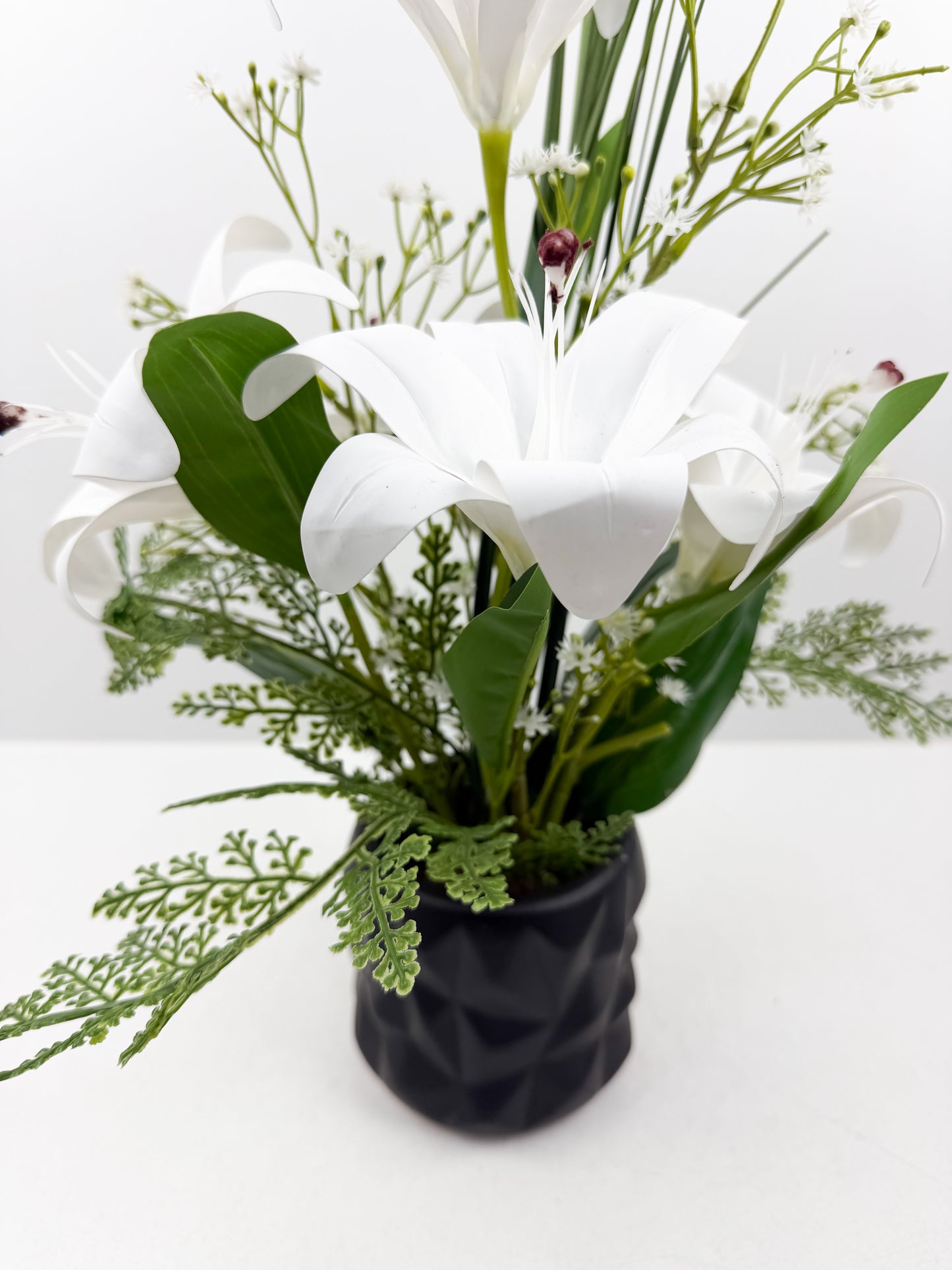 Fleurs artificielles blanches délicates dans un élégant pot noir en céramique de luxe.