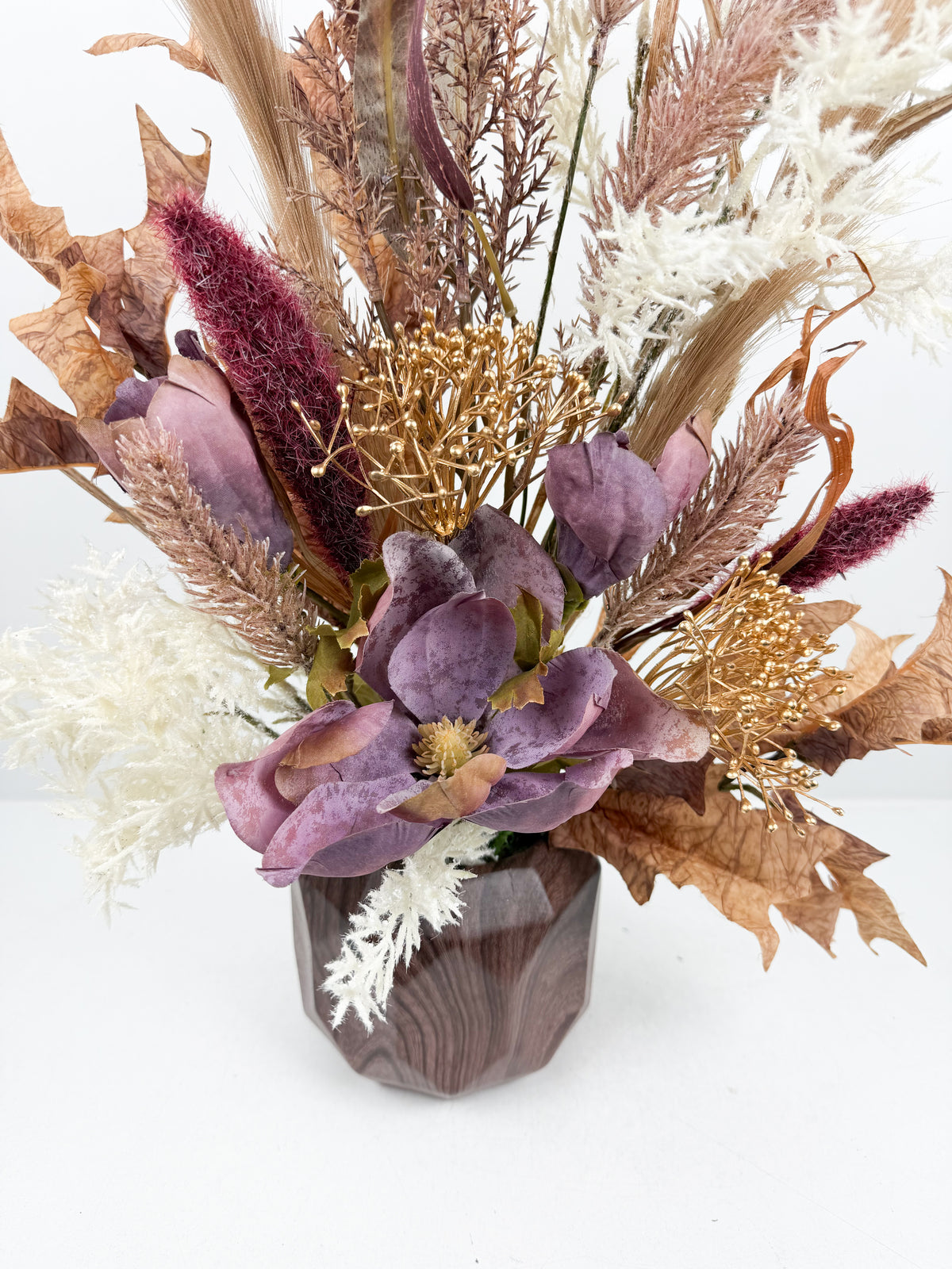 Fleurs séchées délicates dans un élégant vase géométrique en céramique.