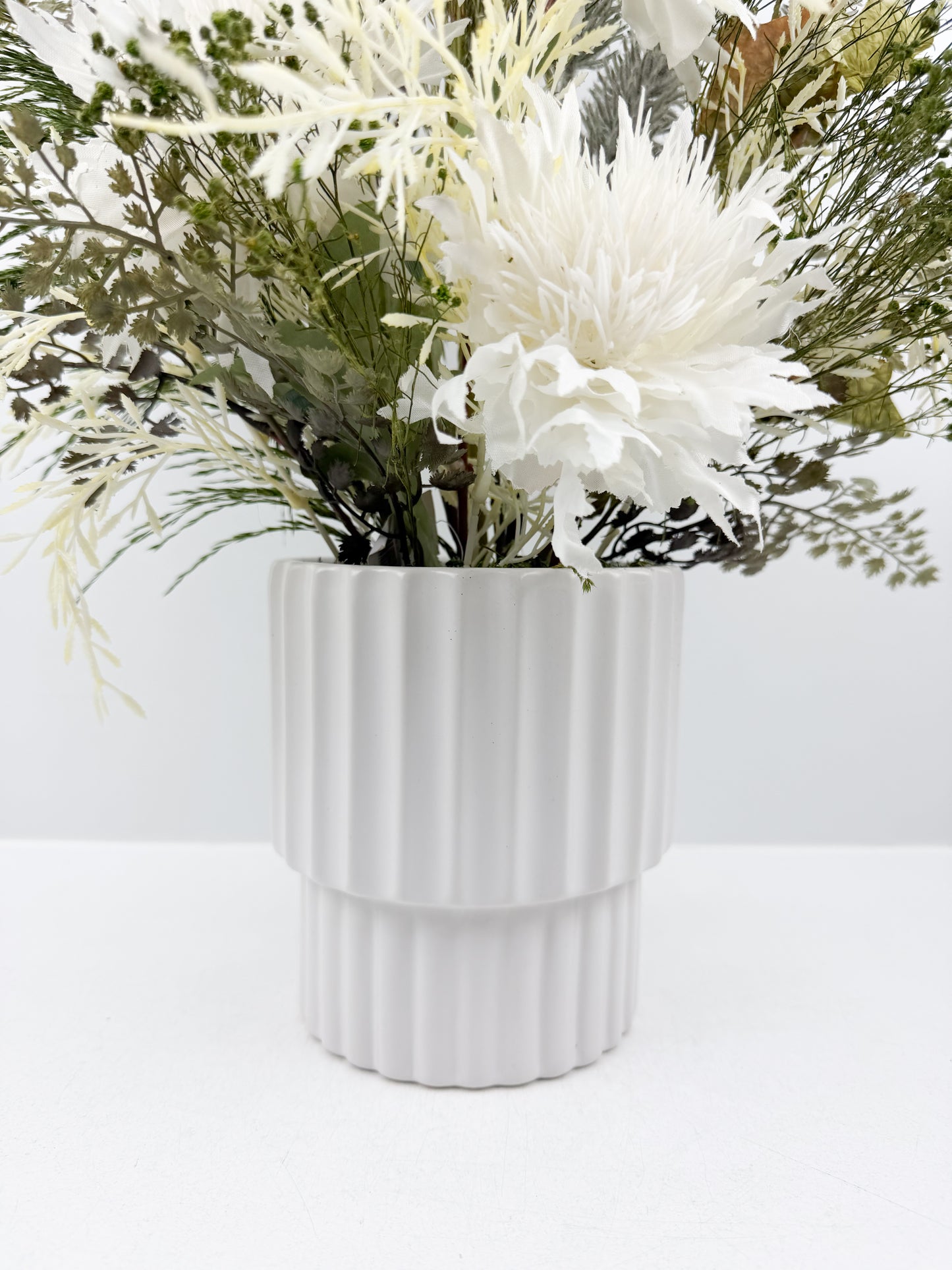 Fleurs artificielles d'une élégance intemporelle dans un vase blanc aux lignes épurées