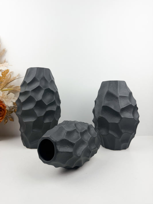 Trio de vases en noir carbone aux formes sculpturales épurées.