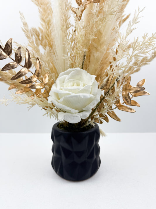 Fleurs séchées beige rehaussée d'une fleur blanche délicate dans un vase en céramique noir aux lignes épurées