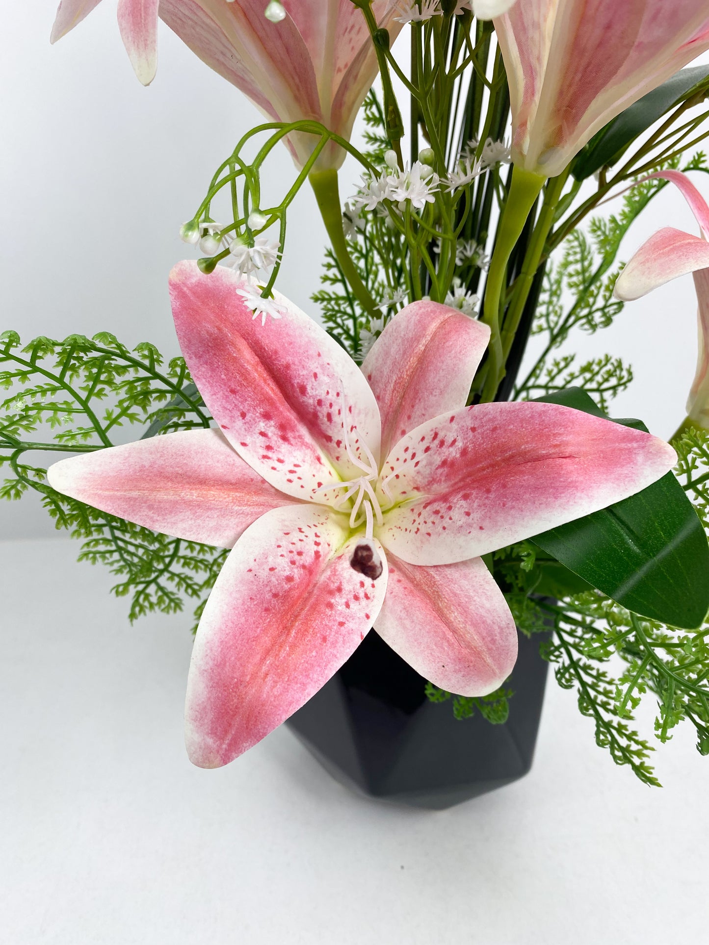 Vase noir avec fleurs artificielles rose et blanc