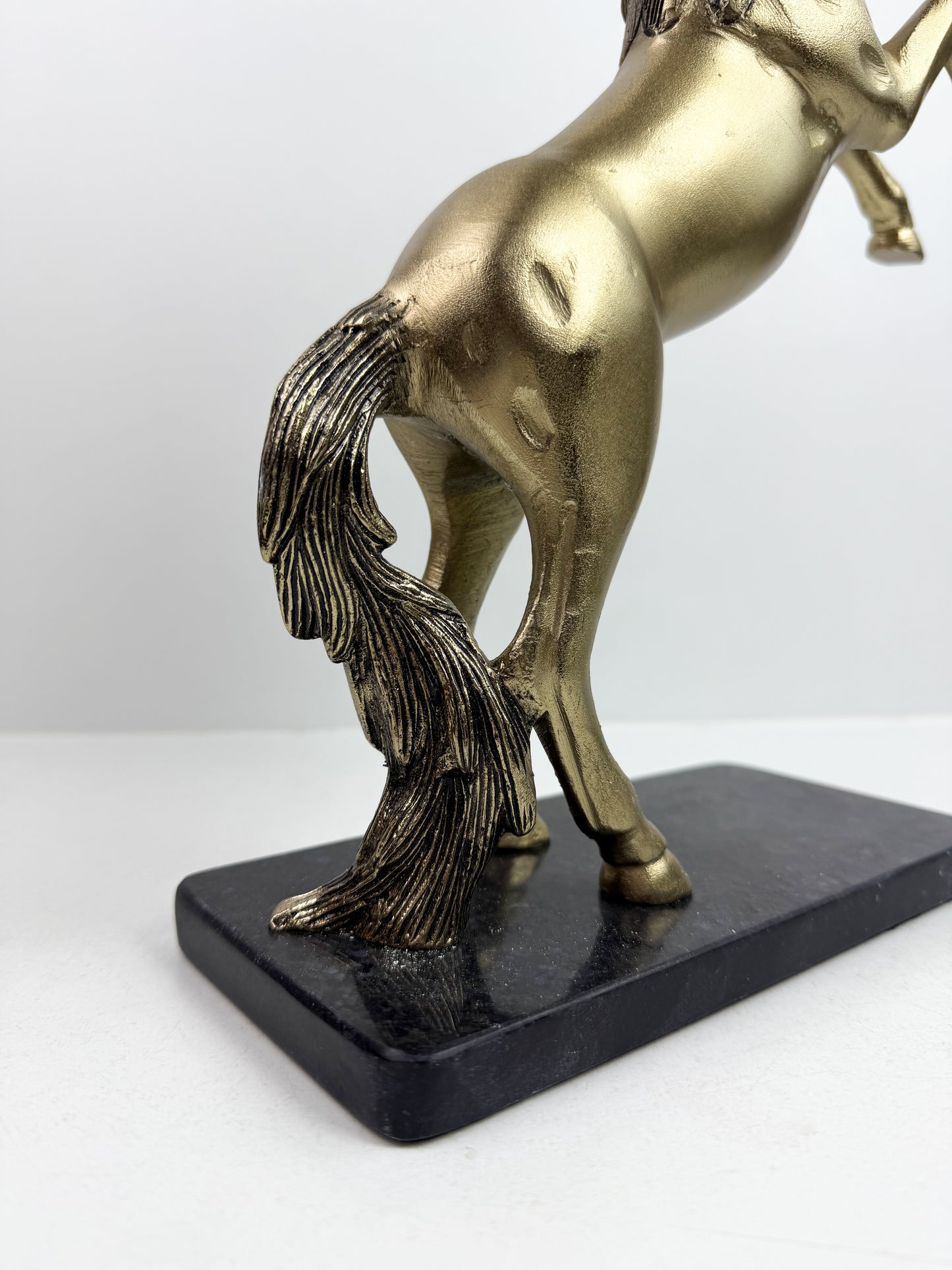 Statue de cheval cabré en résine avec une finition bronze sur un socle noir.