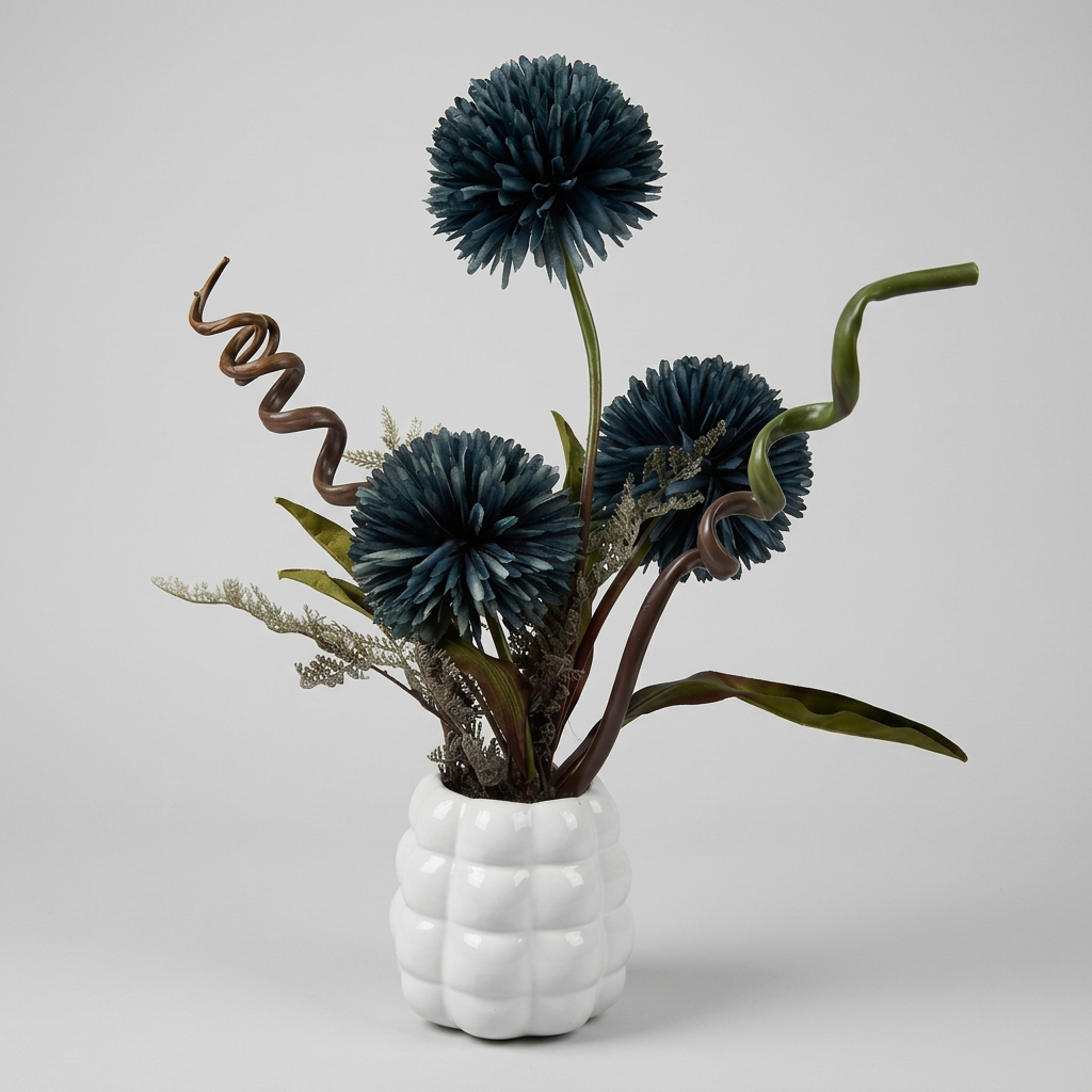 Fleurs artificielles élégantes en forme de pompons éclatantes dans un vase blanc de forme ronde.
