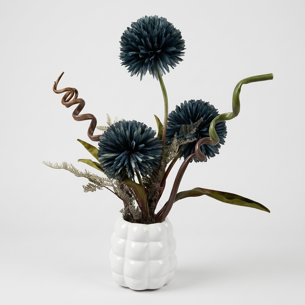 Fleurs artificielles élégantes en forme de pompons éclatantes dans un vase blanc de forme ronde.