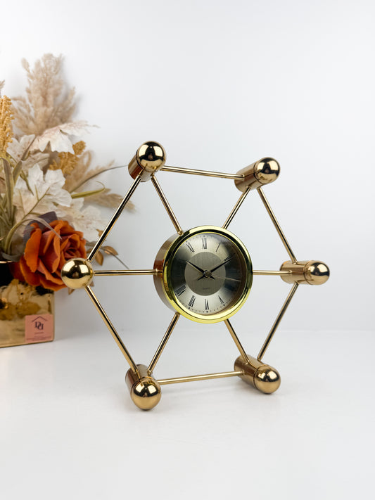 Horloge décoratif en métal doré aux lignes géométriques épurées.