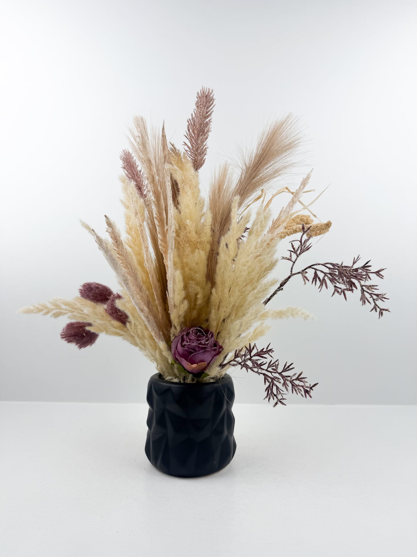 Fleurs séchées aux teintes chaudes et naturelles, présenté dans un élégant vase noir