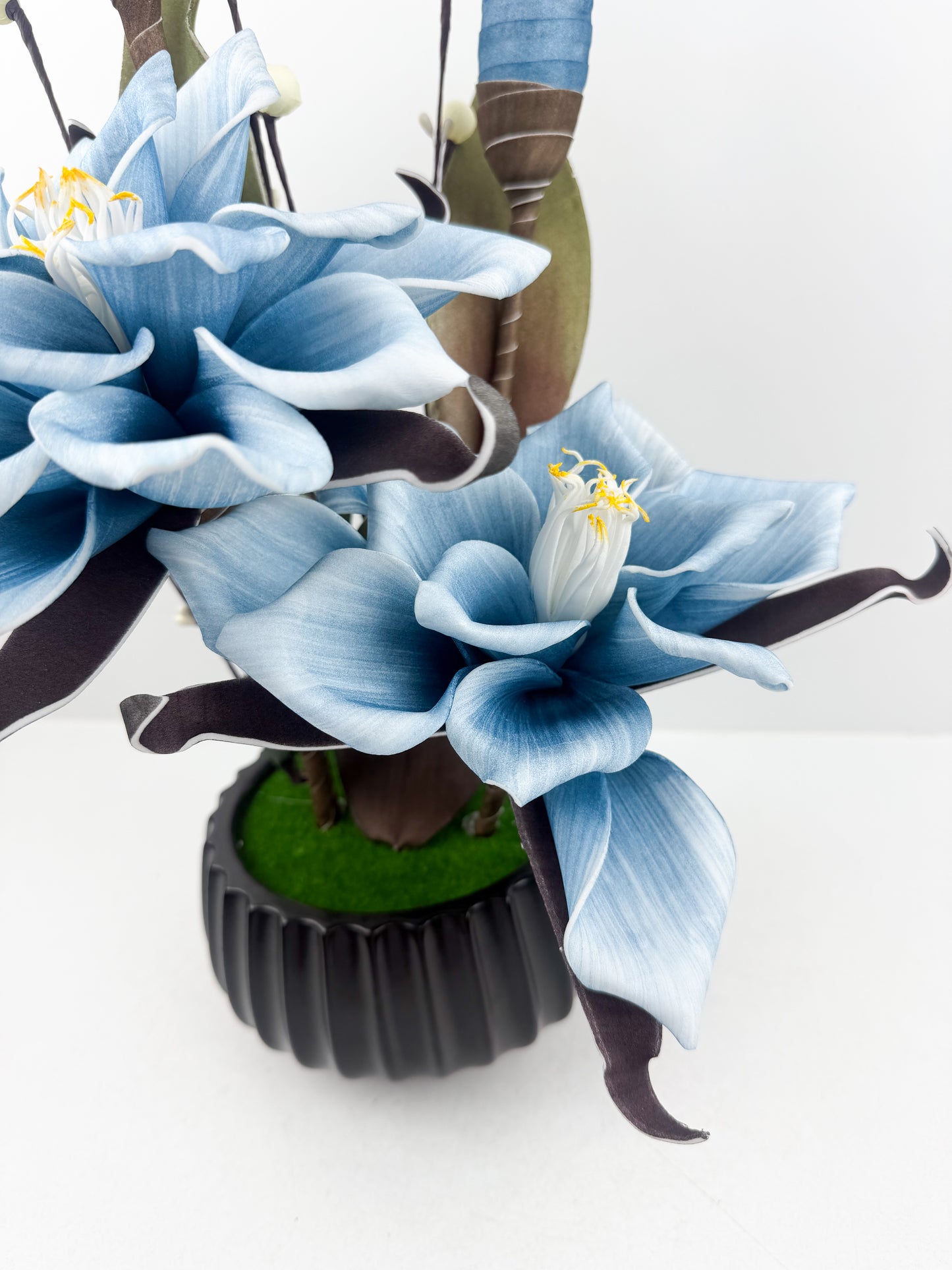 Fleurs bleu artificielles de qualité dans un pot noir haut de gamme