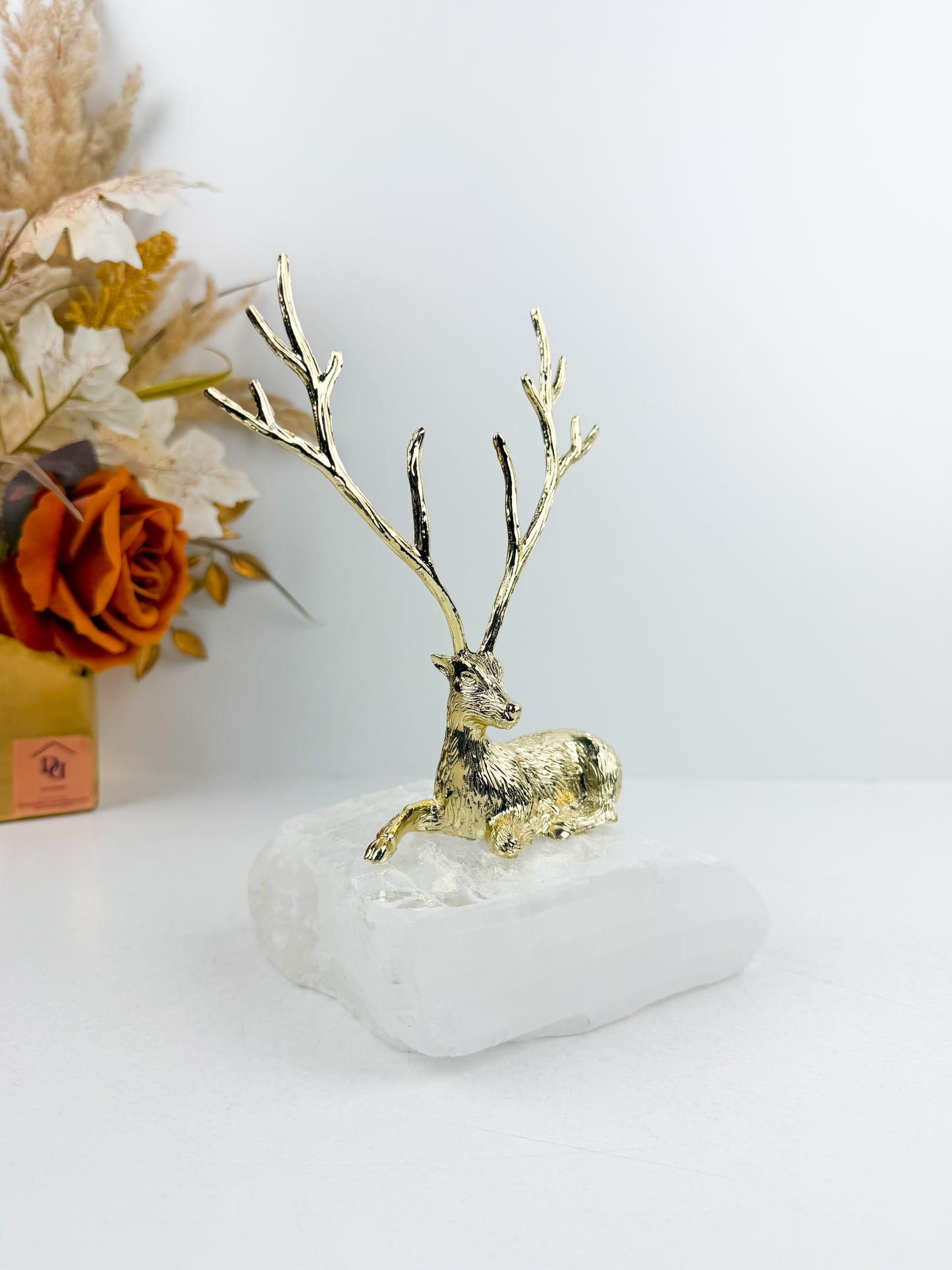 Sculpture gazelle dorée élégante montée sur un socle en pierre blanche de haute qualité.