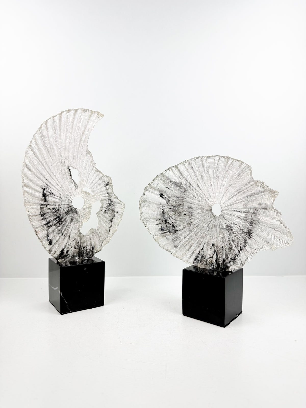 Sculpture décorative plissée en résine sur un socle en cristal noir élégant.