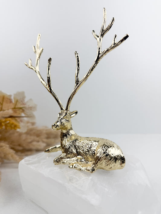 Sculpture gazelle dorée élégante montée sur un socle en pierre blanche de haute qualité.