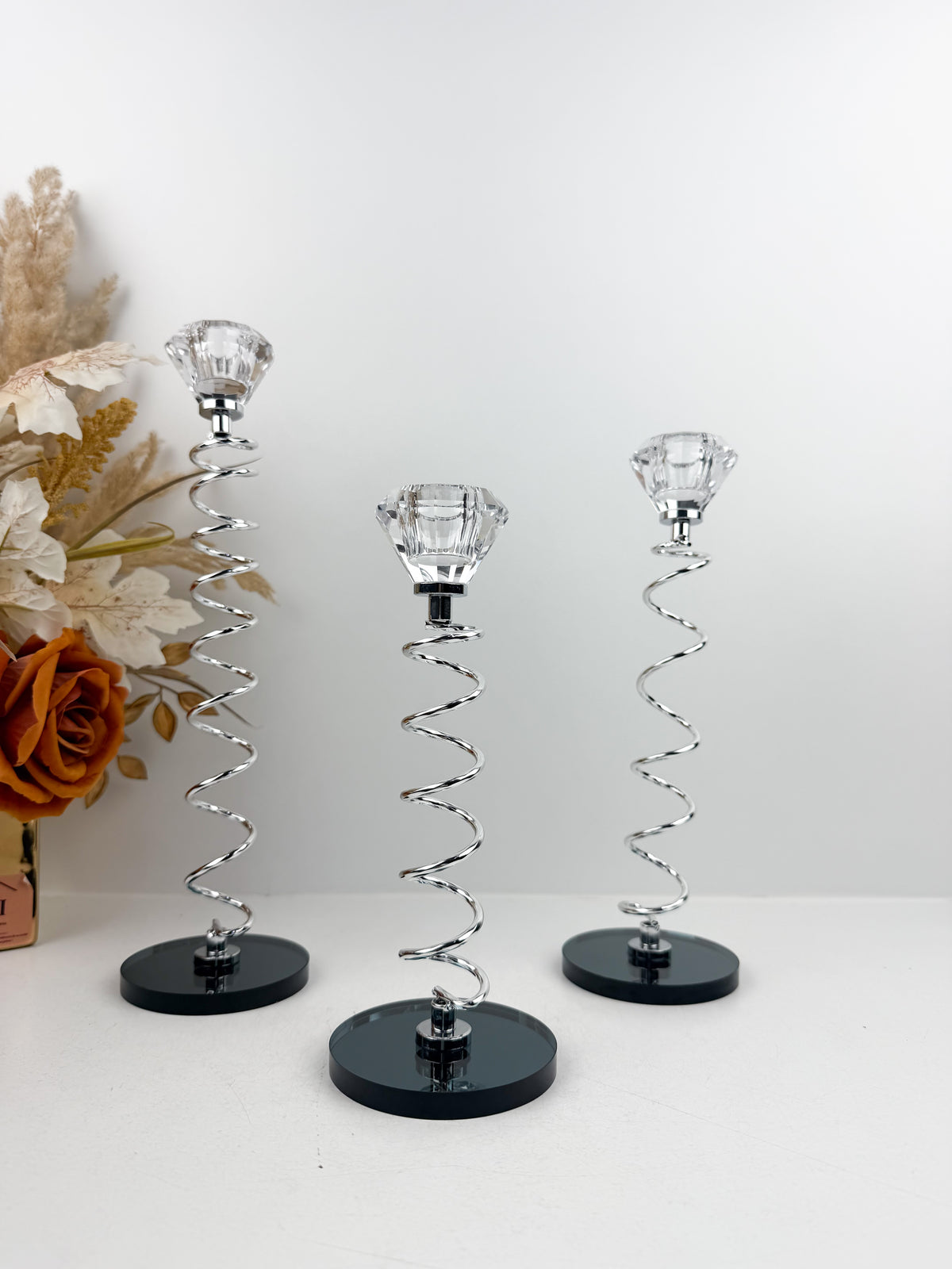 Trio de Bougeoirs en cristal argentée sur un socle noir.
