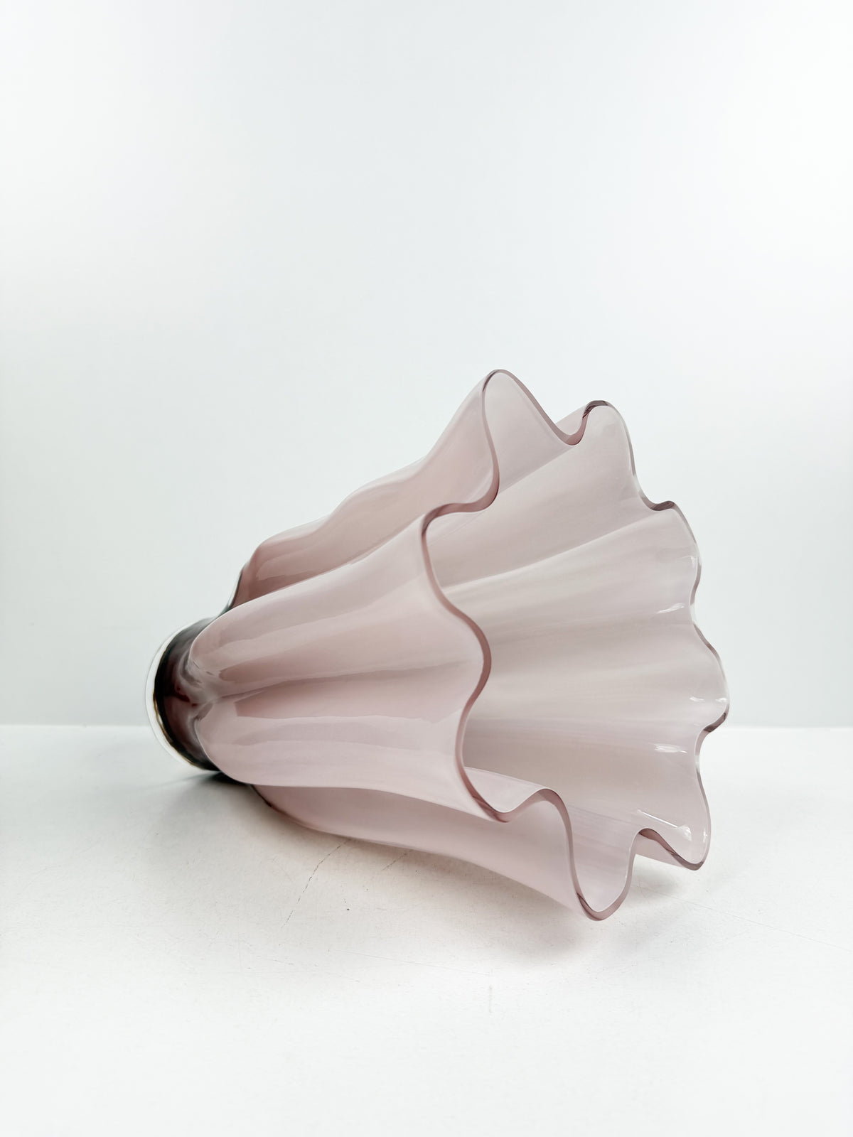 Vase décoratif sculpté rose aux bords ondulés et motifs plissés.