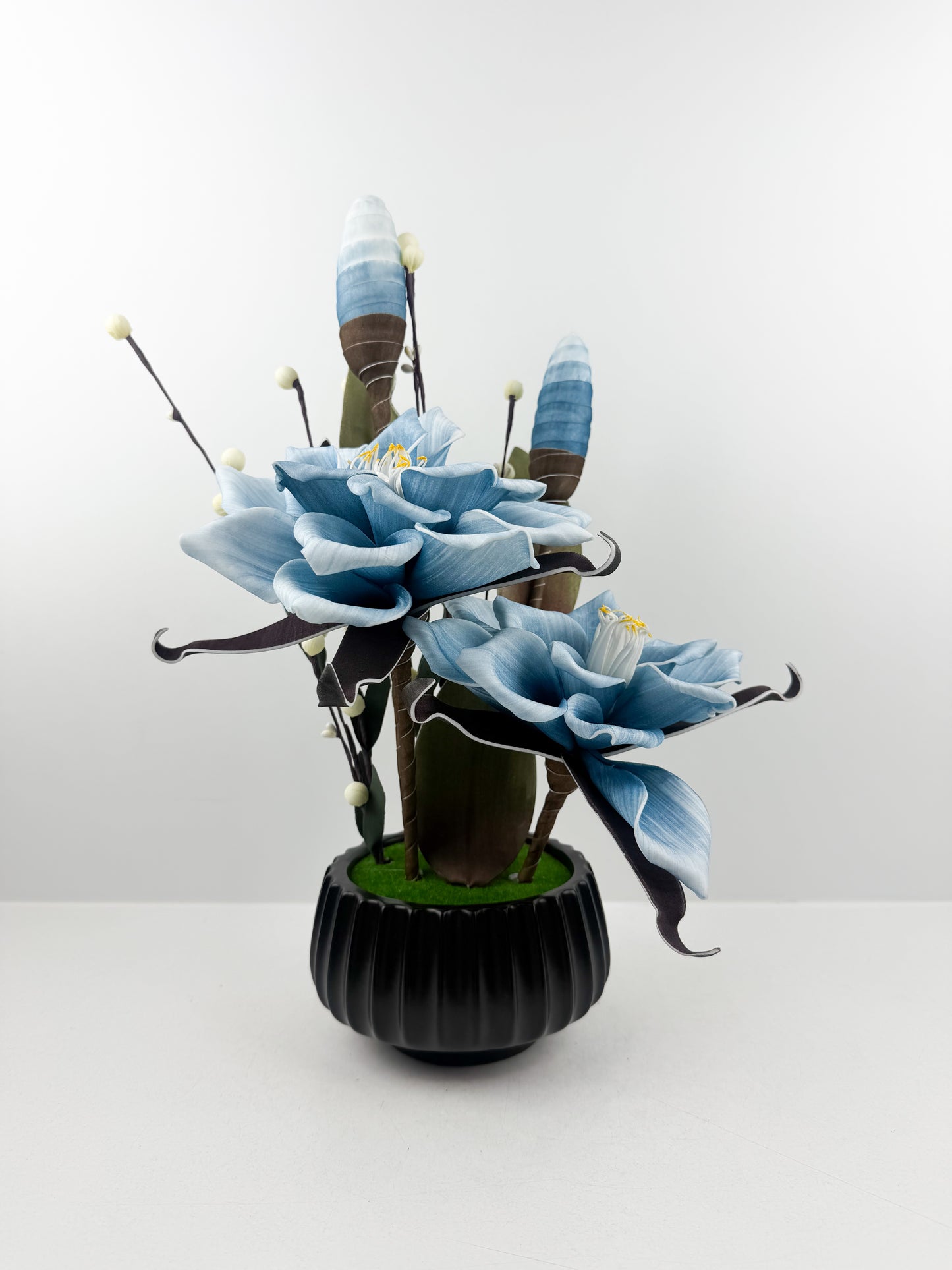 Fleurs bleu artificielles de qualité dans un pot noir haut de gamme