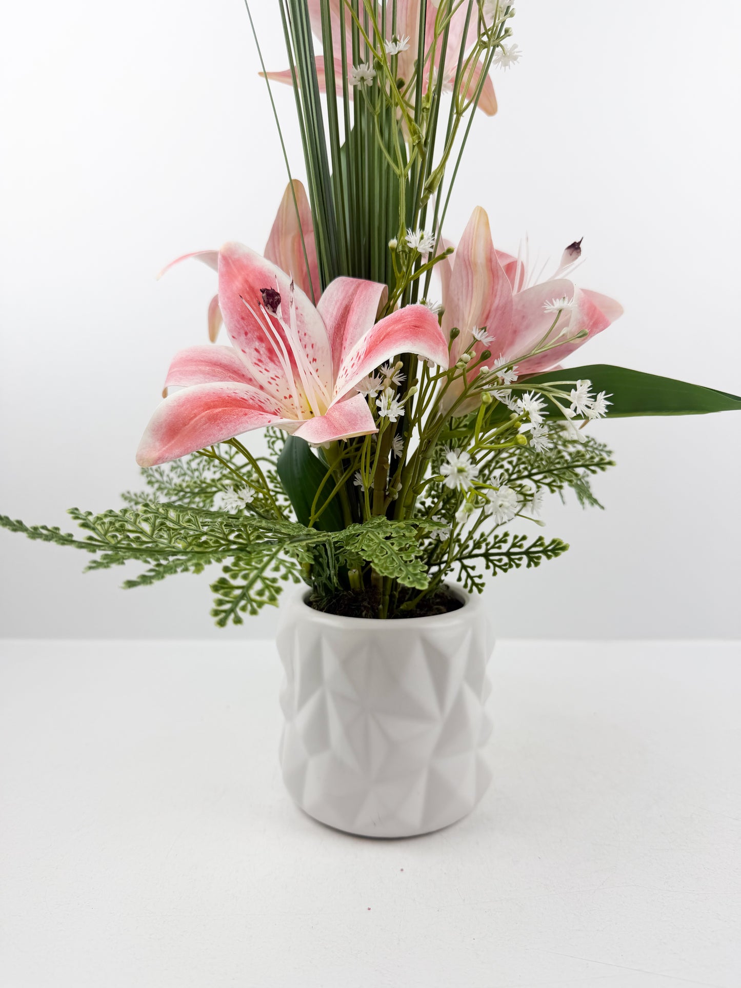 Fleurs artificielles roses  délicates dans un élégant pot blanc en céramique de luxe.