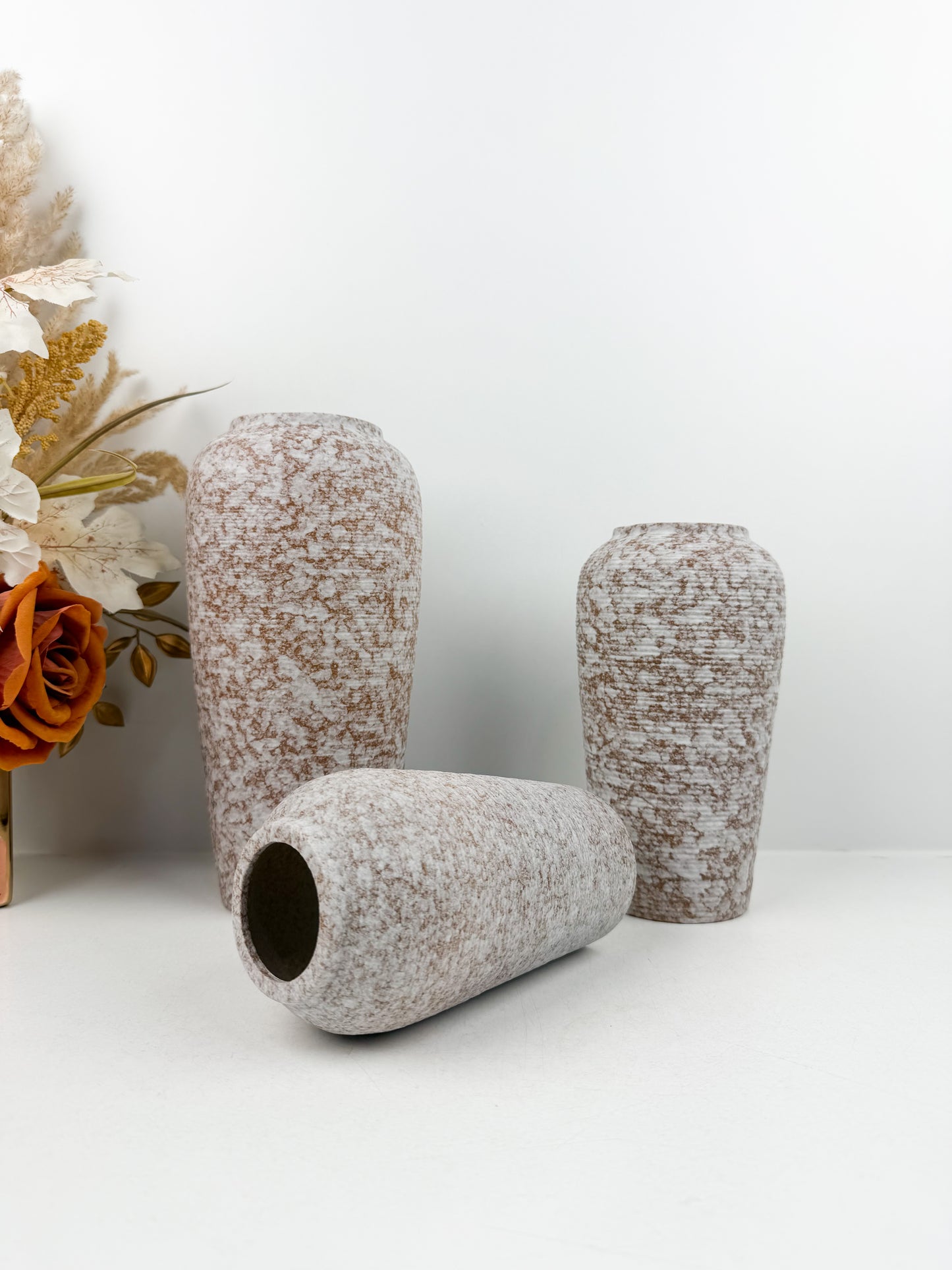 Trio de vases aux teintes marron et blanc en céramique alliant élégance et raffinement.