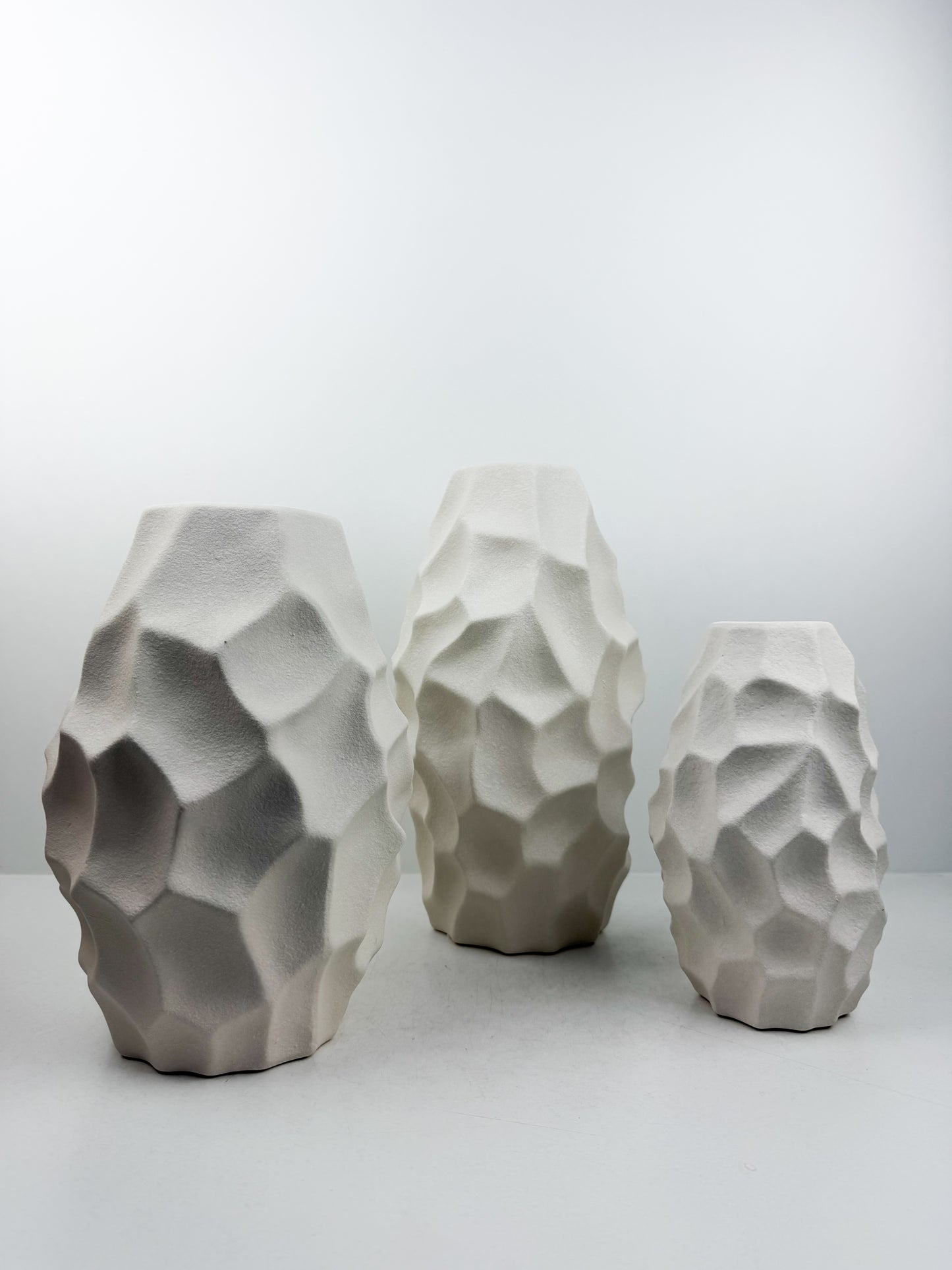 Trio de vases blanches aux formes sculpturales épurées.