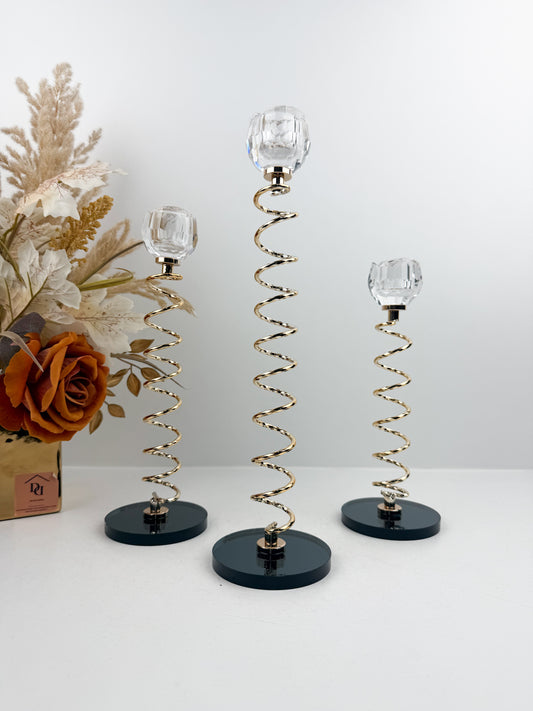 Trio de Bougeoirs en cristal doré sur un socle noir.