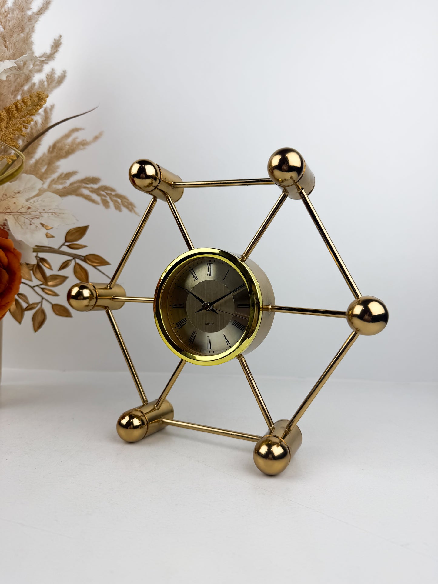 Horloge décoratif en métal doré aux lignes géométriques épurées.