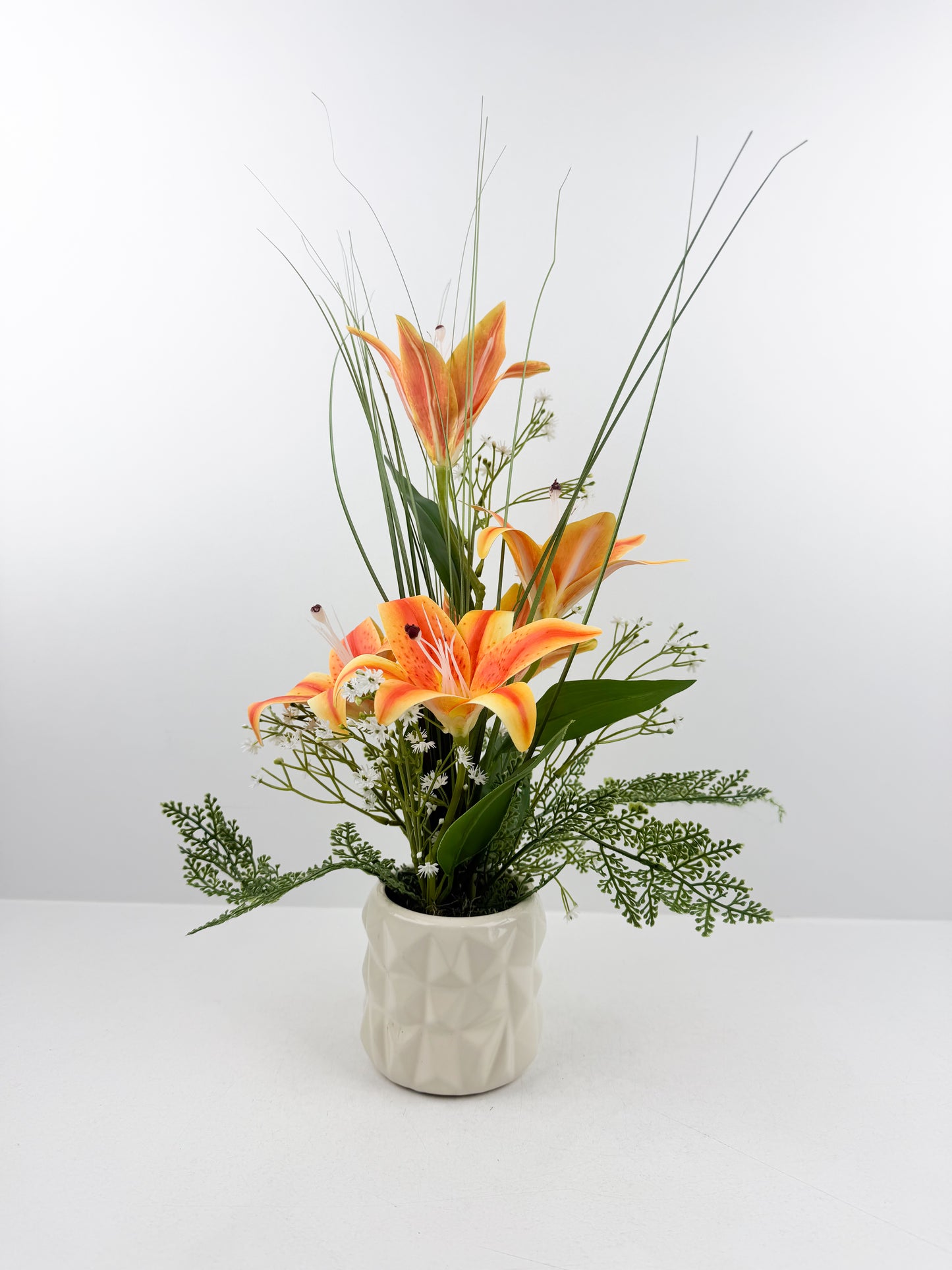 Fleurs artificielles orange  délicates présentées dans un élégant pot blanc en céramique de luxe