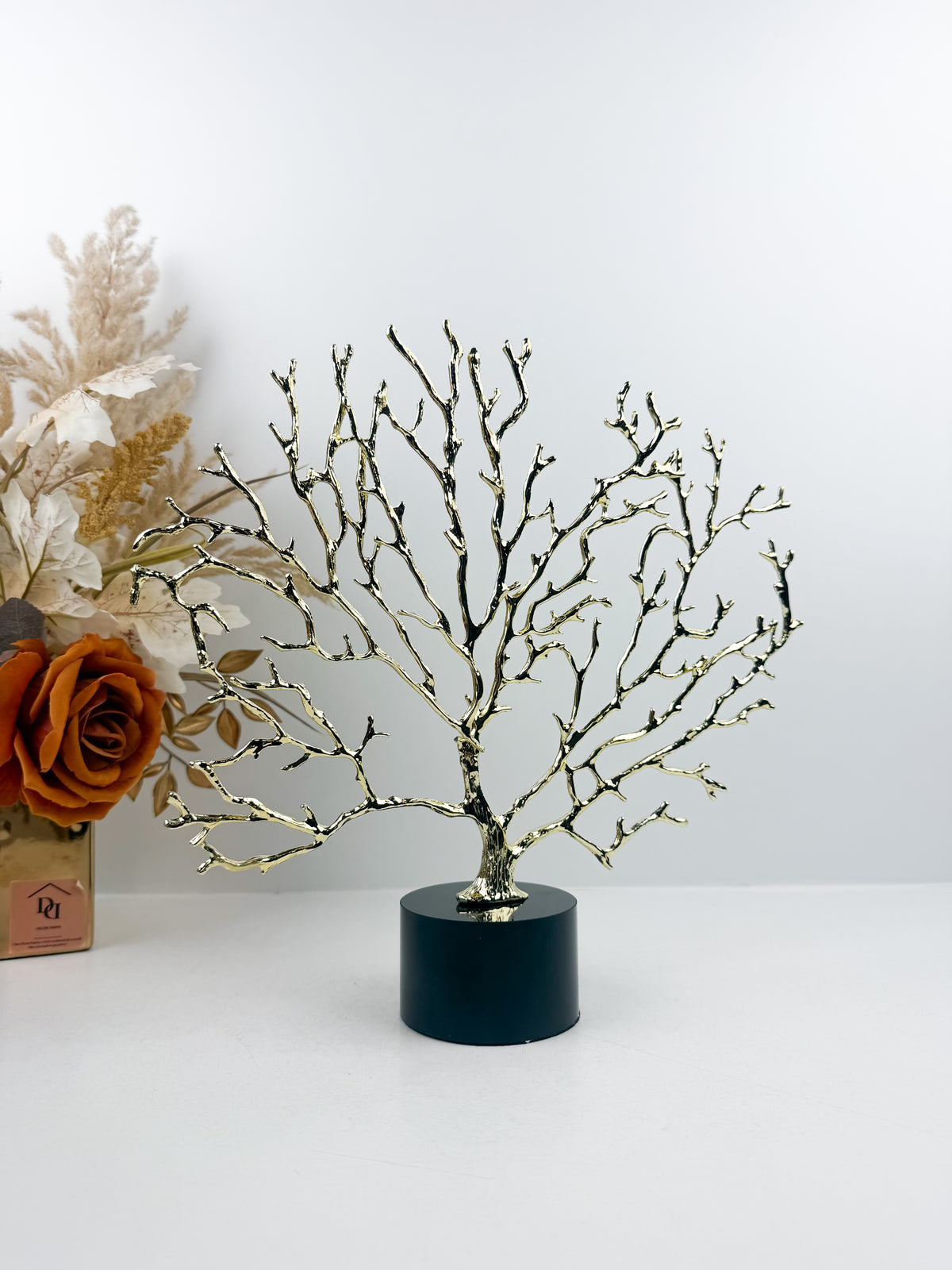 Arbre décoratif sculptural doré sur un socle en cristal noir.