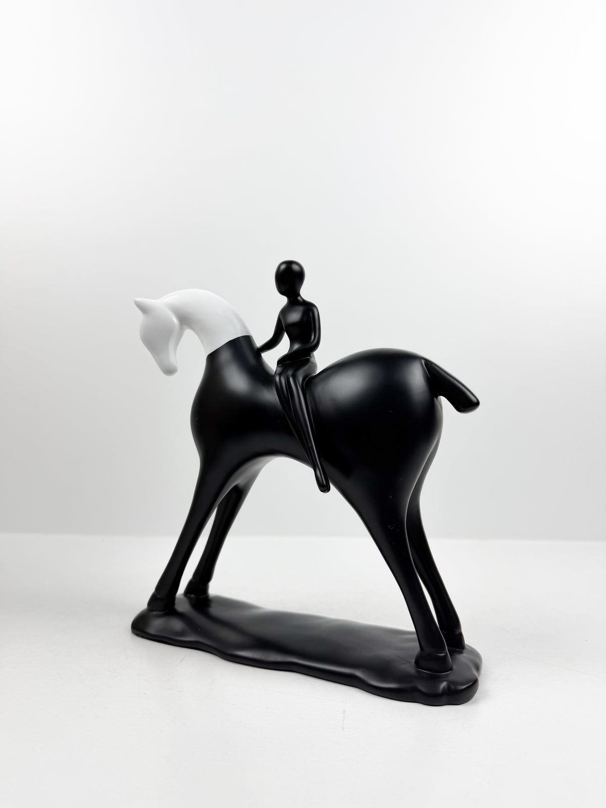 Sculpture décorative équestre moderne en noir et blanc représentant un cavalier stylisé sur son cheval.