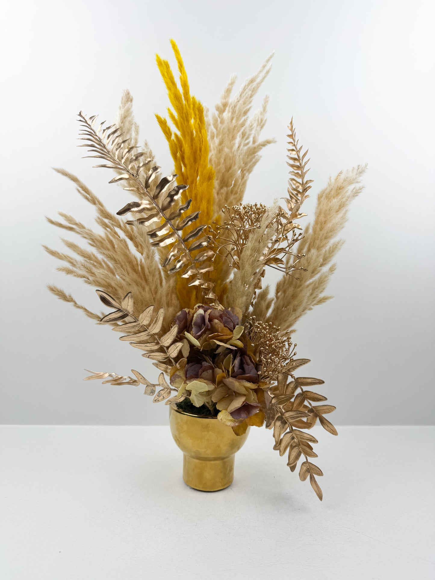 Fleurs séchées marron foncé arrangé avec élégance dans un vase en céramique doré
